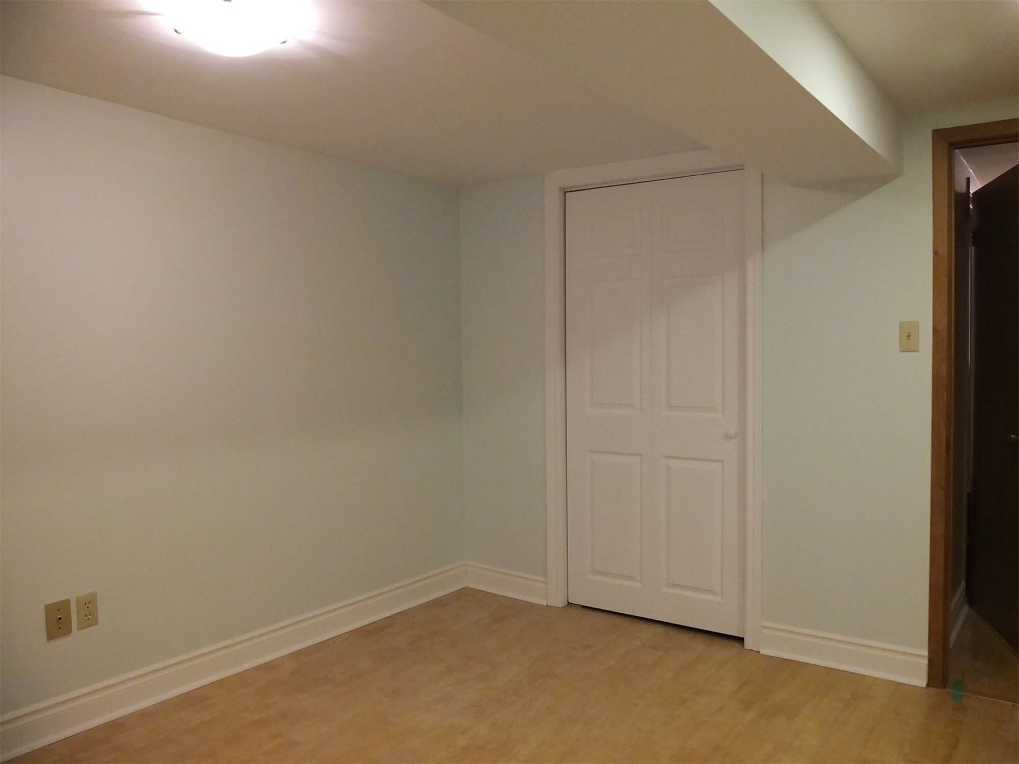 This Oshawa interior renovation project features a refreshed basement room with newly painted walls, upgraded baseboards, and durable hardwood-style flooring. The clean white closet door and updated trim details create a simple yet modern look, while the smooth ceiling and improved lighting enhance overall brightness. The space is designed to be functional and versatile, suitable for use as a guest room, home office, or additional living area. Completed by a professional Toronto Renovation Company, this project reflects careful finishing work and practical interior enhancement.