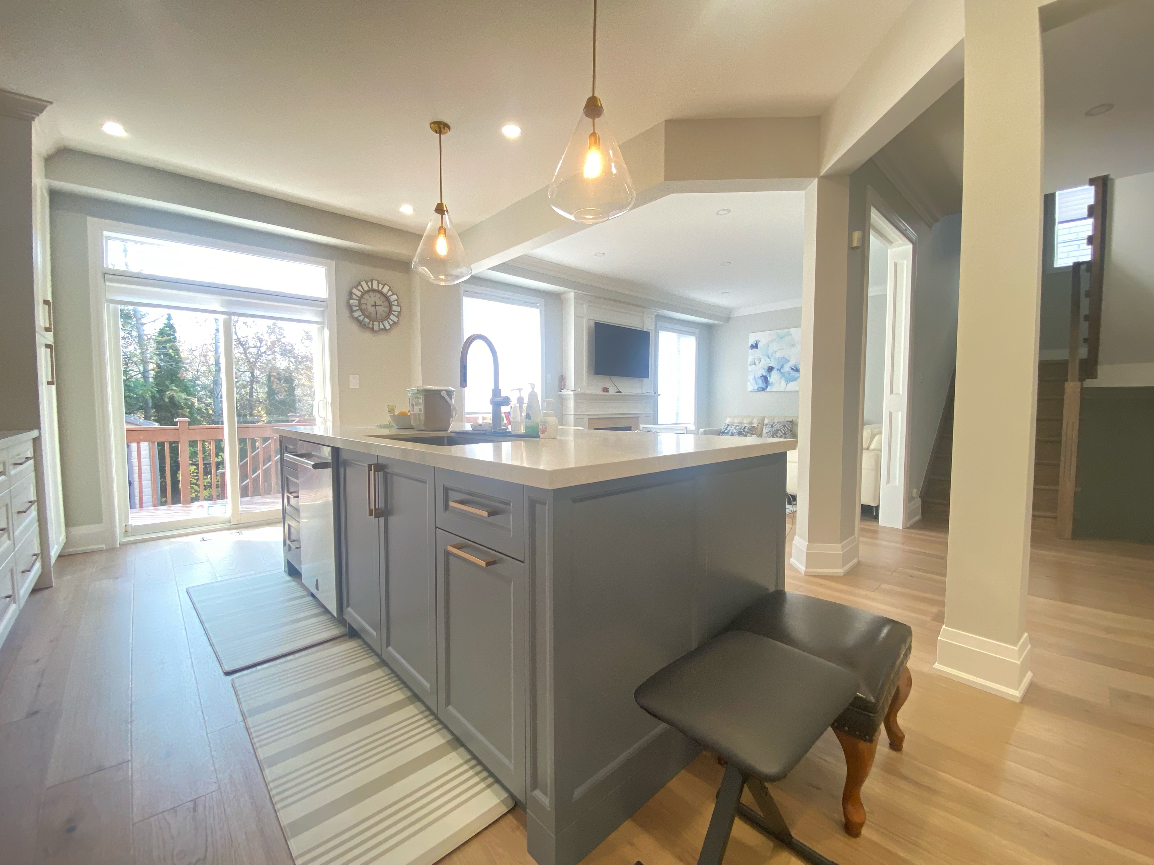 An open-concept kitchen island designed as part of a Richmond Hill interior renovation, featuring integrated seating, custom cabinetry, quartz countertops, and warm pendant lighting. The island functions as a central hub for cooking, casual dining, and family interaction, seamlessly connecting the kitchen to adjacent living spaces.