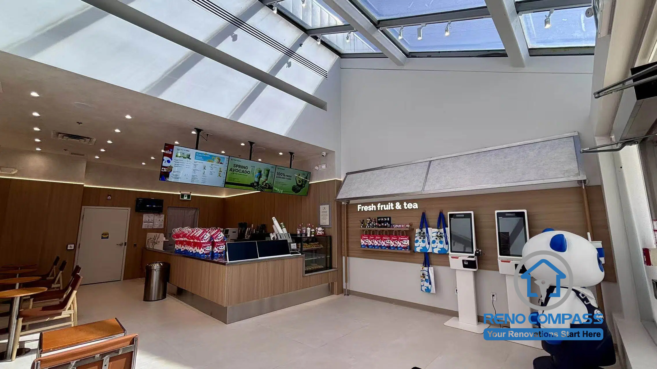 Completed TEABYDO bubble tea shop renovation in Richmond Hill featuring a bright open-concept café interior with large skylight ceiling, custom beverage counter, self-order kiosks, wood-tone commercial finishes, and modern customer seating layout. This commercial renovation project was completed by Reno Compass serving Richmond Hill, Toronto, and the GTA.