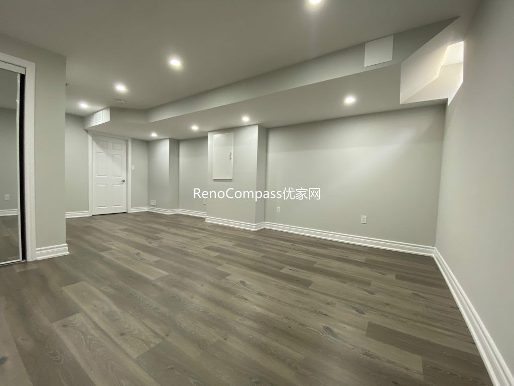 Spacious open-concept basement renovation in Richmond Hill featuring warm-toned laminate flooring, soft lighting, and sleek wall finishes. Reno Compass redesigned this area to maximize comfort and usability.