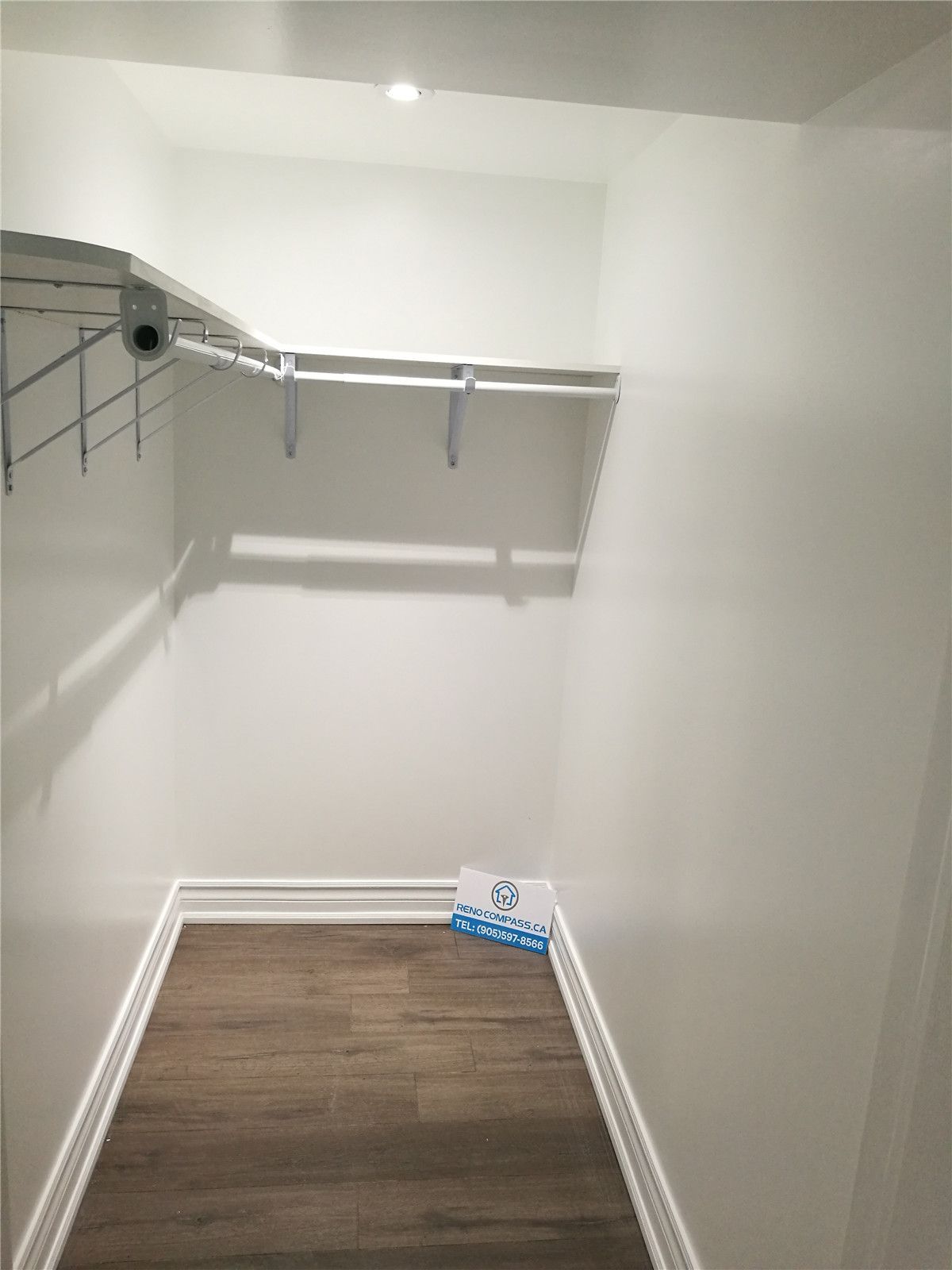 Custom walk-in closet from a Pickering interior renovation project, featuring built-in shelving, hanging rails, new flooring, and clean white finishes. This functional storage upgrade improves organization and everyday use, completed by a professional Toronto renovation company.