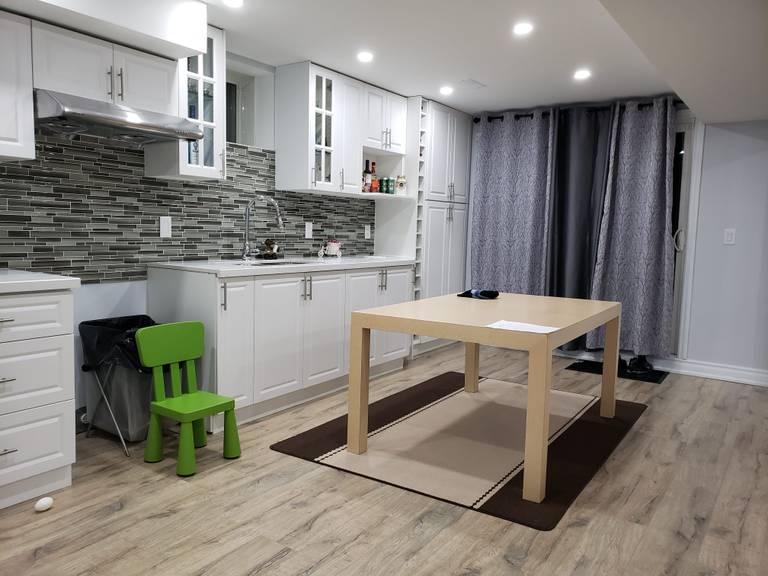 This modern basement kitchen renovation in Newmarket, Toronto features custom white cabinetry, a contemporary mosaic tile backsplash, and upgraded recessed pot lighting to create a bright and functional space. The layout includes ample storage, extended countertop workspace, and durable wood-look flooring designed for long-term basement use. Neutral tones and clean finishes enhance the sense of openness, while the integrated dining area makes the space ideal for family living or rental potential. Completed by an experienced Toronto renovation company, this basement upgrade focuses on practicality, modern aesthetics, and efficient use of space.