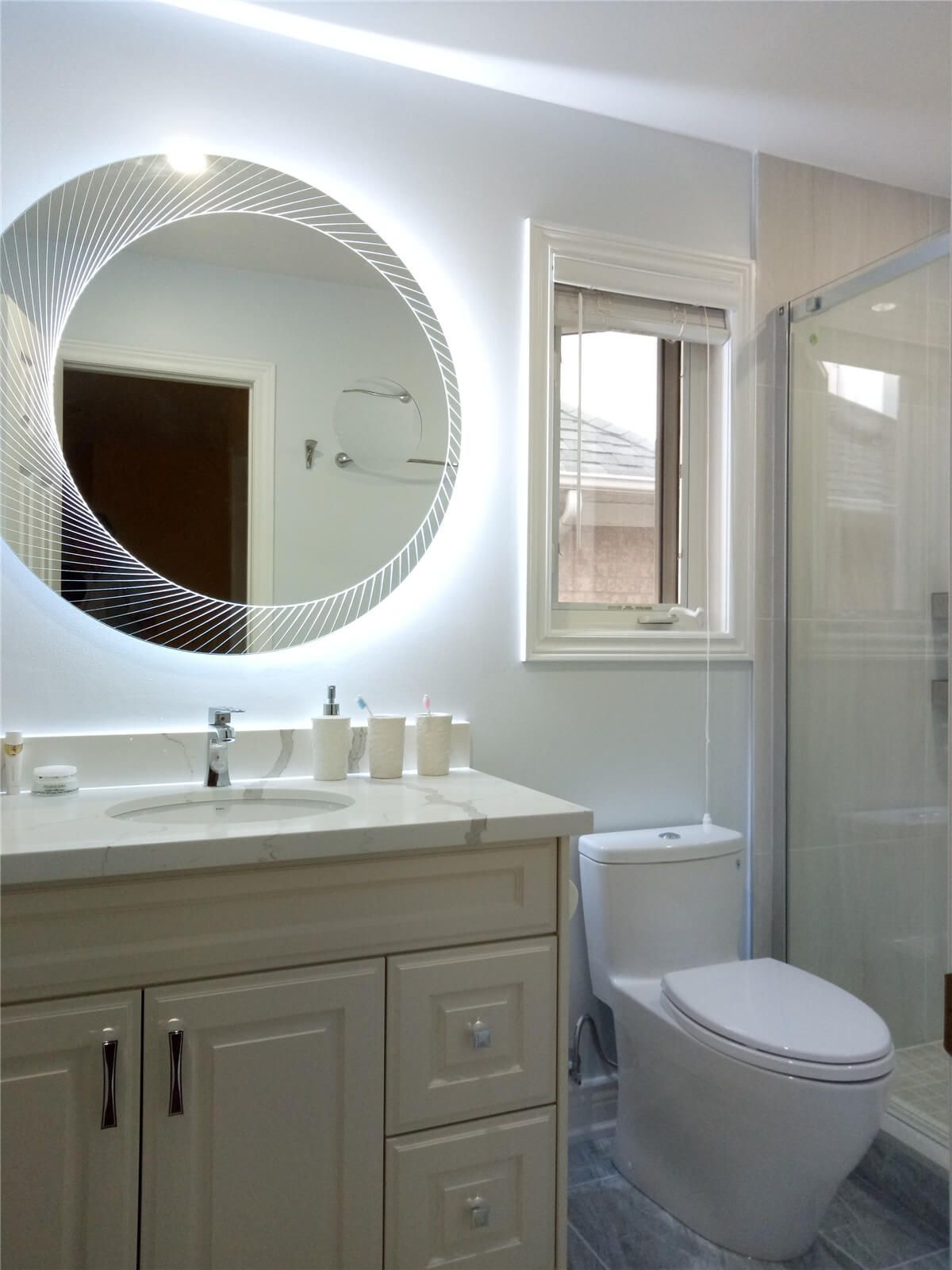 This Richmond Hill bathroom renovation highlights a bright and modern layout featuring a custom vanity with quartz countertop, illuminated LED mirror, and a sleek frameless glass shower enclosure. Neutral tones and quality finishes create a clean, spa-like environment while maximizing functionality and comfort. The upgraded fixtures and efficient space planning bring a fresh contemporary feel, enhancing both daily living and long-term home value through thoughtful interior renovation.