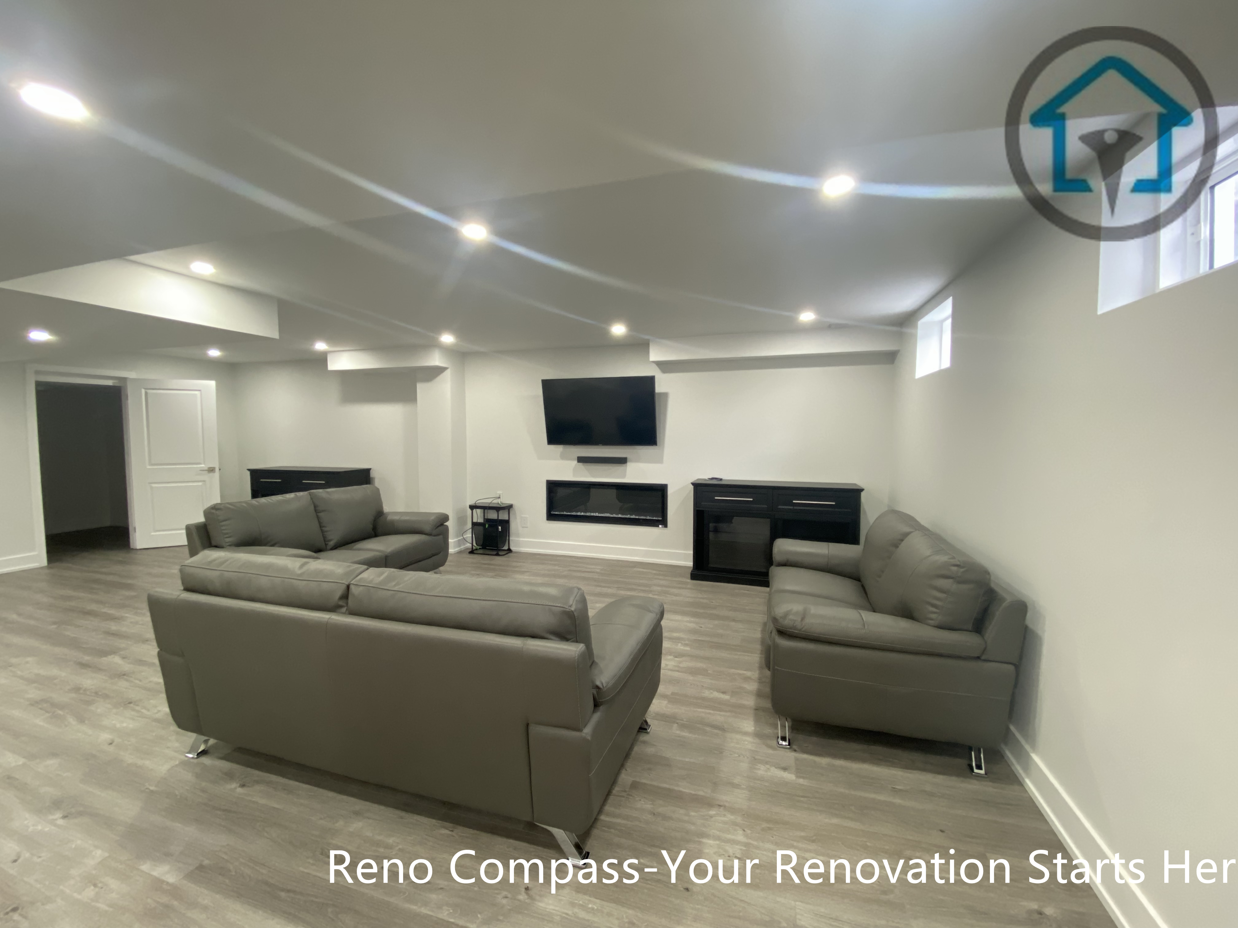 This image highlights a finished basement home theatre and entertainment area in Newmarket completed by a professional Toronto renovation company. The space features a wall-mounted TV, modern linear fireplace, custom storage cabinets, and recessed ceiling lighting. Paired with wood-look flooring and a clean, symmetrical layout, this basement entertainment zone is ideal for movie nights, family relaxation, or enhancing overall basement functionality.