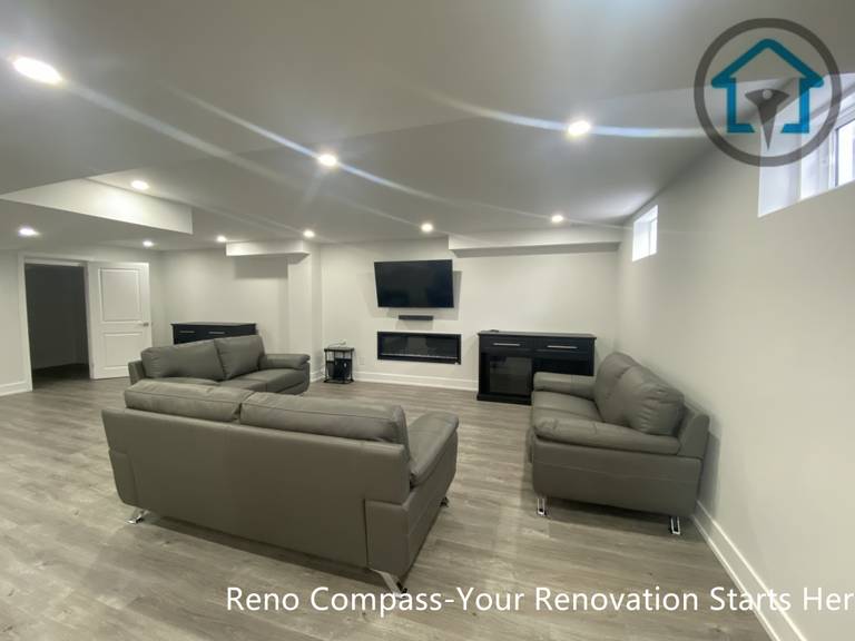 This image highlights a finished basement home theatre and entertainment area in Newmarket completed by a professional Toronto renovation company. The space features a wall-mounted TV, modern linear fireplace, custom storage cabinets, and recessed ceiling lighting. Paired with wood-look flooring and a clean, symmetrical layout, this basement entertainment zone is ideal for movie nights, family relaxation, or enhancing overall basement functionality.