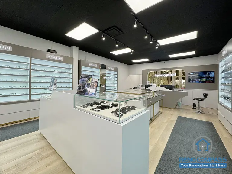 This Mississauga optical store interior renovation showcases an open retail layout with central eyewear display islands, wall-mounted shelving, and integrated lighting. The design improves customer flow, enhances product visibility, and creates a clean, modern commercial environment for optical retail.