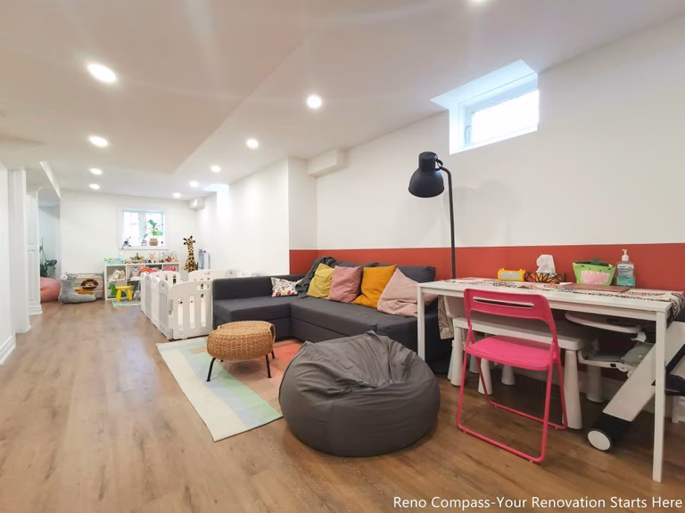 This image features a renovated basement family room in Vaughan, designed as a flexible living space suitable for relaxation, play, and everyday family activities. The layout combines comfortable seating, soft lighting, and durable wood flooring to create a welcoming and practical environment. Recessed ceiling lights and a small window provide balanced illumination, while the open arrangement allows the space to adapt to different uses such as lounging, children’s activities, or casual gatherings. This basement renovation demonstrates the thoughtful space planning and construction quality delivered by a professional Toronto renovation company focused on functional residential interiors.