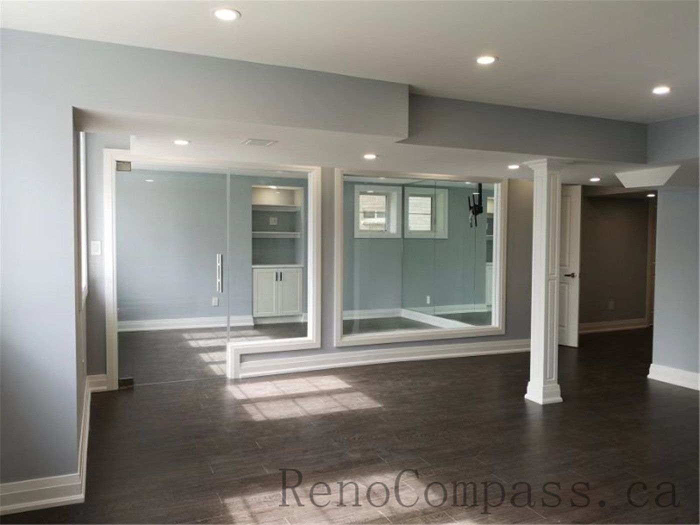 An open-concept basement in Aurora redesigned with soft gray tones, recessed lighting, and sleek trim work. The minimalist, modern aesthetic creates a bright and inviting lower-level living space — completed by Reno Compass.
