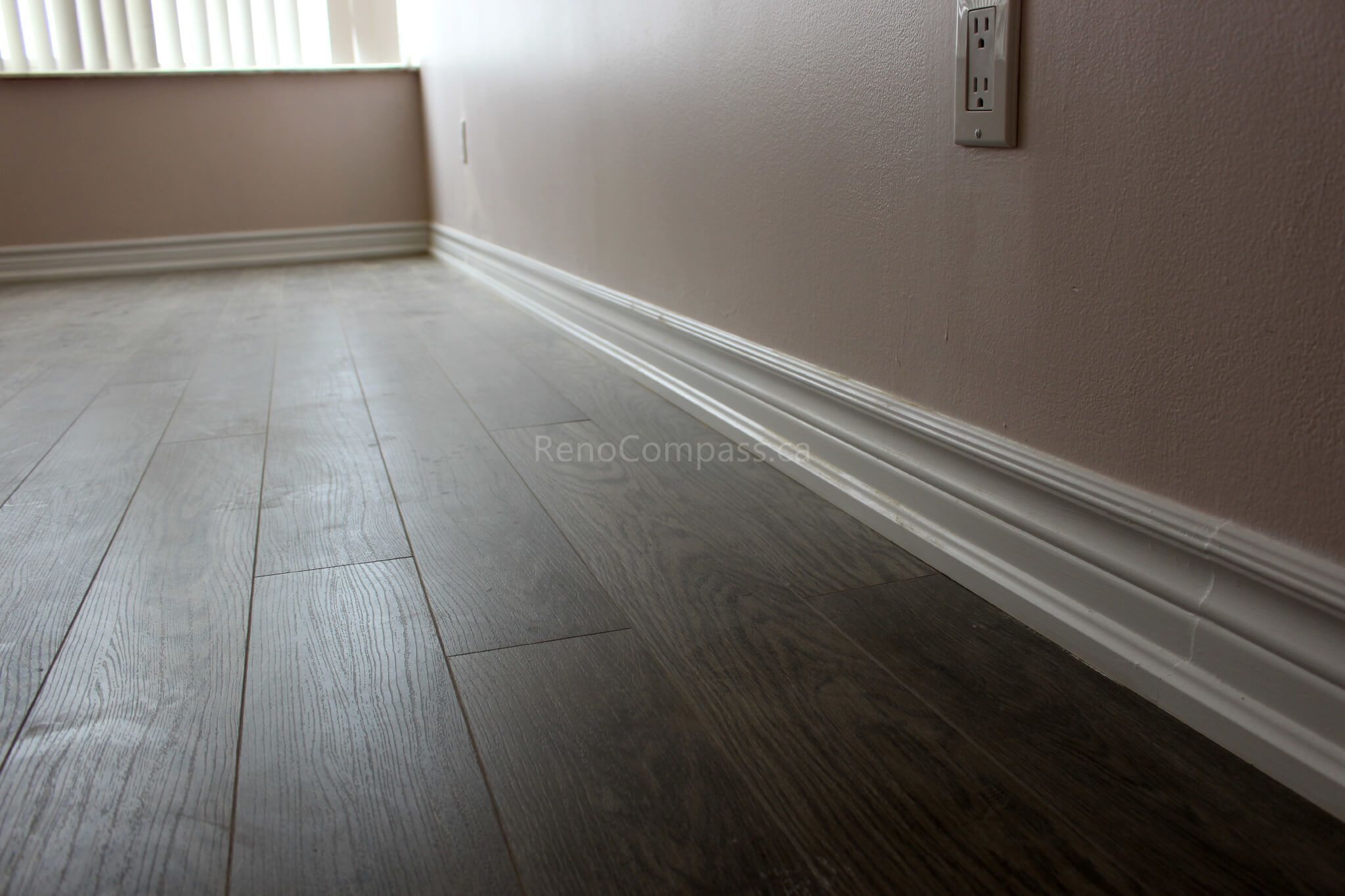 Newly installed dark wood-look luxury vinyl flooring with crisp white baseboards, enhancing the elegance of this Mississauga home renovation. The modern flooring finish blends durability and style, ideal for contemporary interiors.