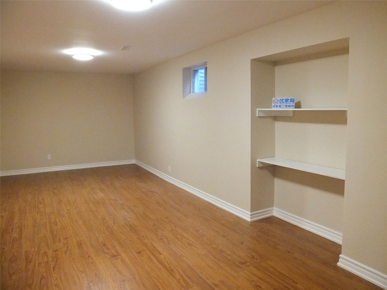 This Markham basement renovation includes a custom built-in wall shelving unit designed to add practical storage and display space. The recessed niche with clean white shelves contrasts beautifully with the warm neutral wall paint and wood-style flooring, creating a functional and visually balanced interior feature. The installation enhances basement organization while maintaining a modern and tidy interior design.
