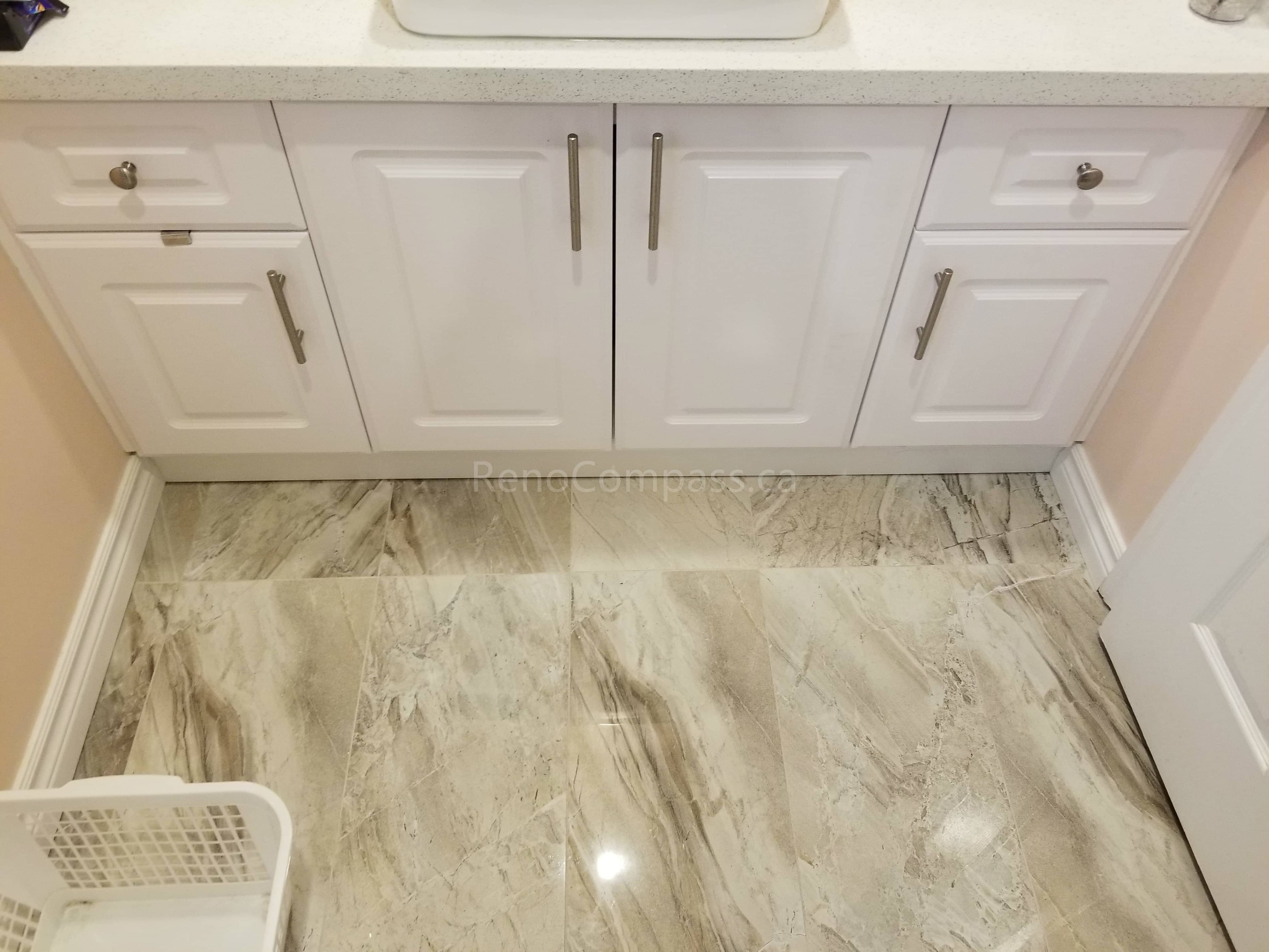 This Markham bathroom renovation includes a newly installed custom vanity with a modern countertop vessel sink and upgraded faucet. The clean white cabinetry provides ample storage while complementing the new floor tiles and overall bathroom design. The refreshed vanity area enhances both functionality and style, creating a bright, organized, and contemporary bathroom space for daily use.