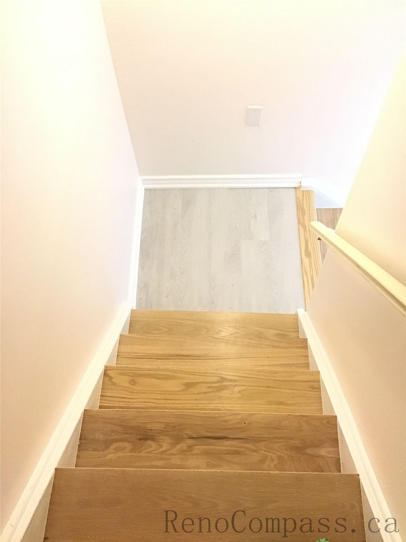 Newly installed modern wooden staircase for this Pickering basement renovation project, featuring natural-tone wood steps, clean white side walls, and a bright contemporary finish. The upgraded basement stairs improve both safety and visual flow, creating a seamless transition to the newly finished lower level. Completed by Reno Compass Inc., a professional Toronto Renovation Company.