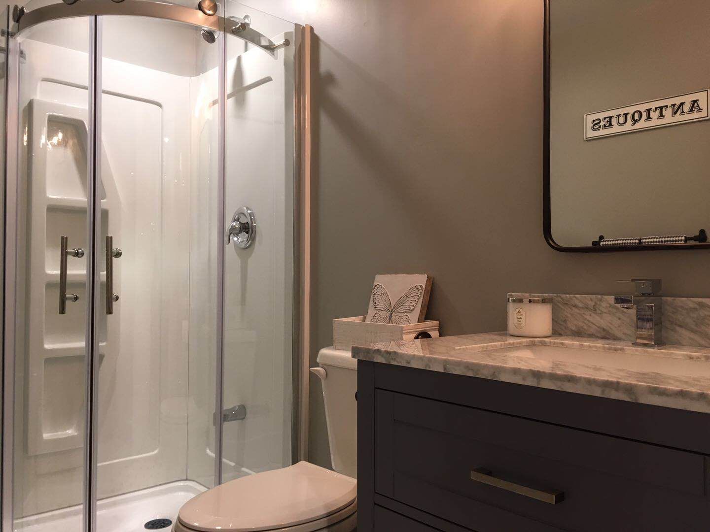 This Richmond Hill basement renovation features a fully upgraded bathroom with a sleek glass shower enclosure, modern fixtures, and a custom vanity with marble countertop. The contemporary design combines functionality and style, creating a clean and comfortable bathroom space that enhances the overall value and convenience of the finished basement.