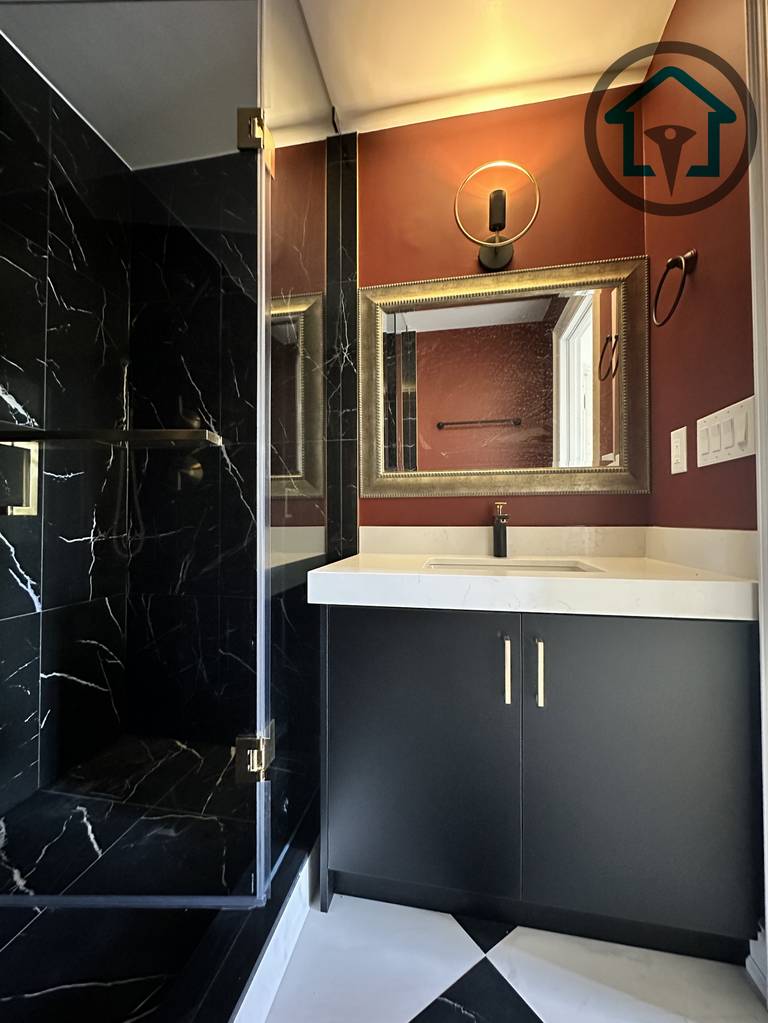 This powder room renovation showcases a dramatic black marble walk-in shower paired with a minimalist vanity and clean-lined fixtures. Frameless glass panels enhance openness while bold material contrast adds visual depth. Completed as part of a North York interior renovation, this space reflects the craftsmanship and design coordination of an experienced Toronto renovation company.