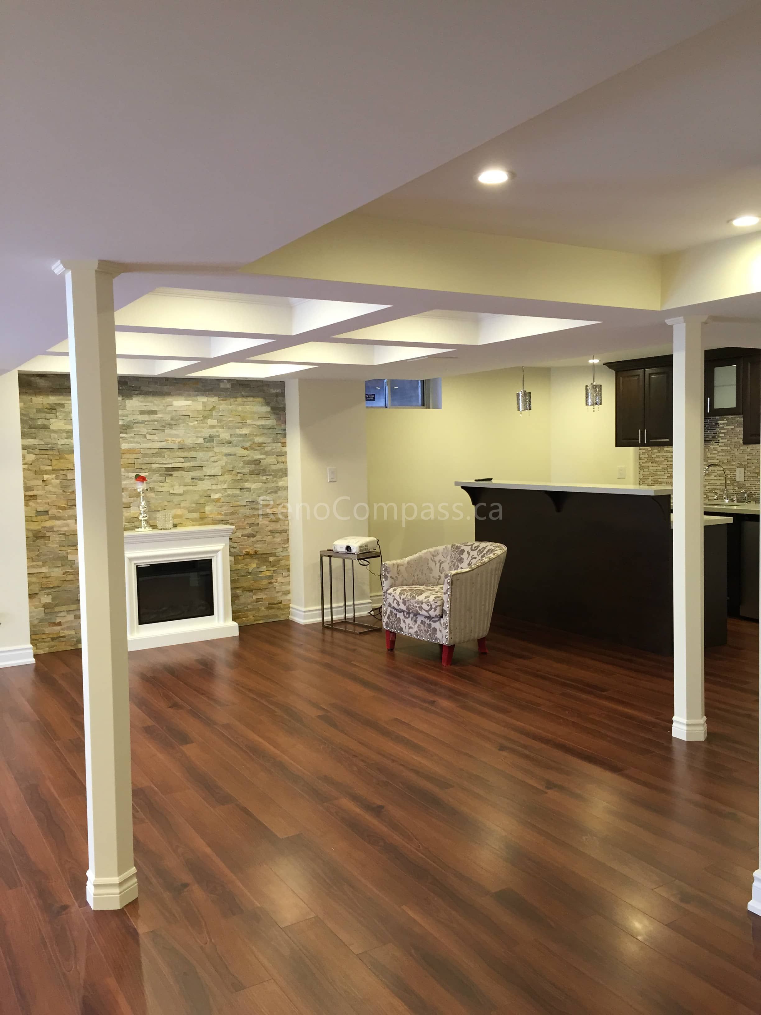 This Toronto basement renovation features a spacious open-concept layout with new hardwood flooring, recessed lighting, and a modern fireplace accent wall. The upgraded basement includes a stylish bar area and support beam finishing to create a warm and functional living space ideal for entertainment and family use. Completed by Reno Compass, a trusted Toronto renovation company, this project highlights quality craftsmanship and practical basement design for modern homes.
