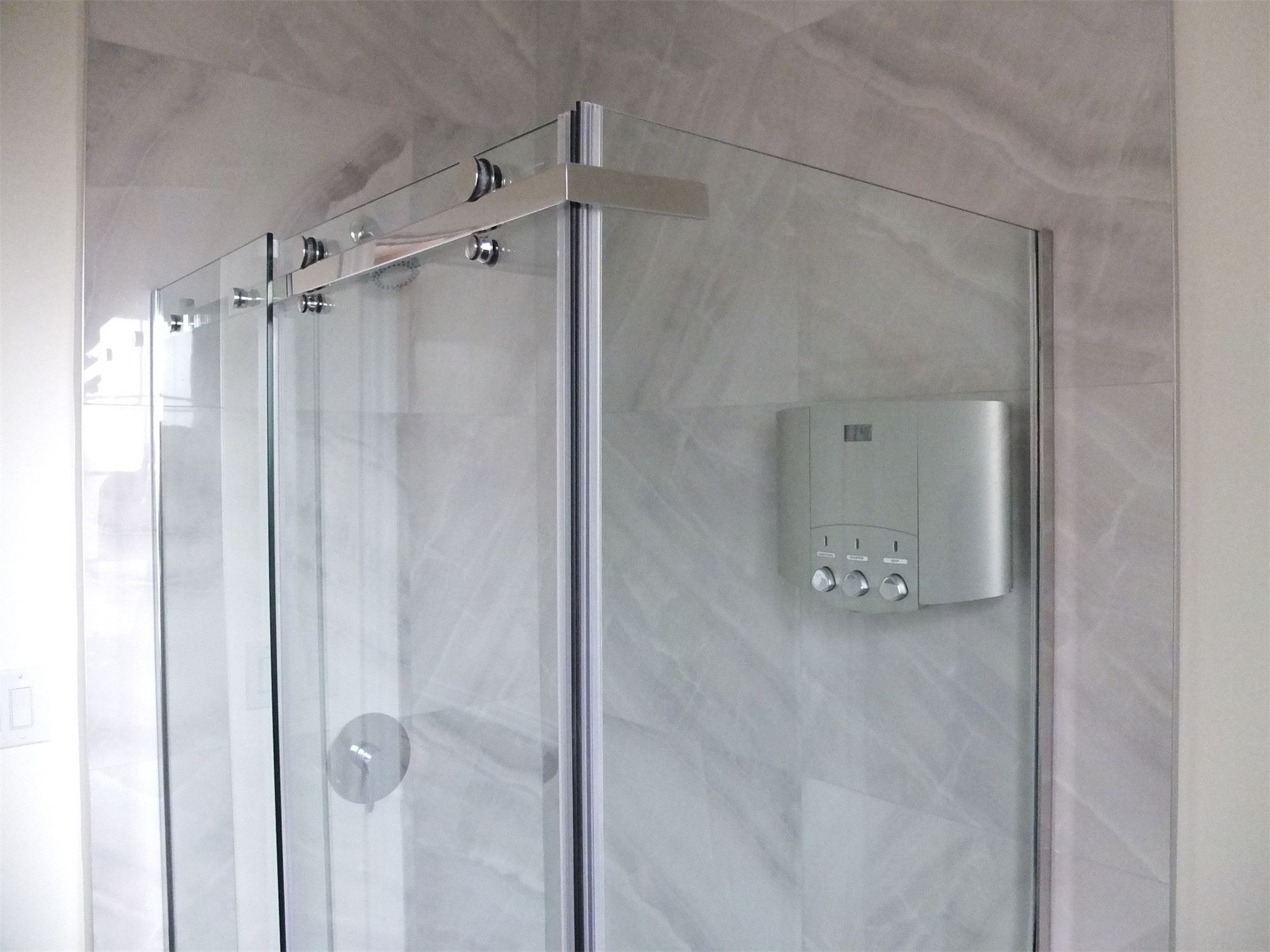 Modern bathroom renovation in a Scarborough home addition project featuring a frameless glass shower enclosure, marble-look wall tiles, and integrated shower system controls. The design enhances both elegance and functionality within the newly expanded residential space.
