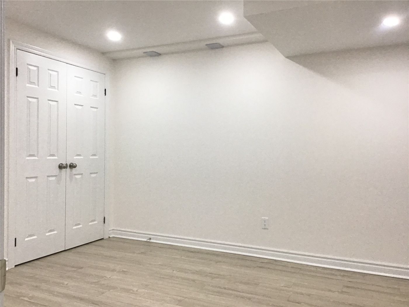 This Aurora basement renovation includes a functional storage room with clean white double closet doors and a minimalist design. The space features durable flooring and recessed lighting, providing an organized and practical solution for additional storage in the finished basement.