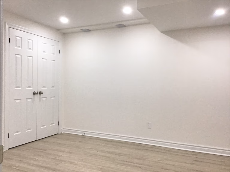 This Aurora basement renovation includes a functional storage room with clean white double closet doors and a minimalist design. The space features durable flooring and recessed lighting, providing an organized and practical solution for additional storage in the finished basement.