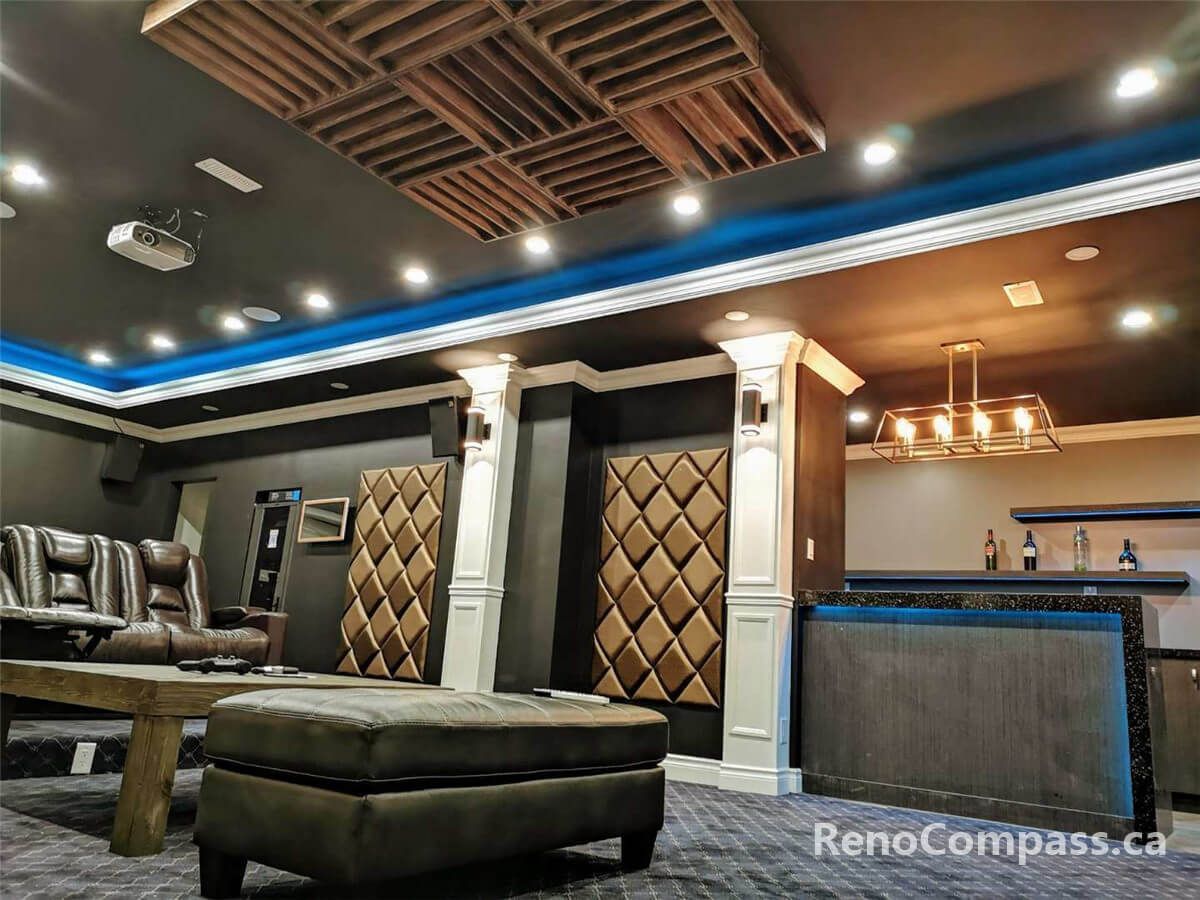 This image showcases detailed ceiling design and acoustic treatment in a custom home theater, featuring recessed lighting, wood acoustic panels, decorative columns, and a seamless transition to the built-in bar area for a refined entertainment space.