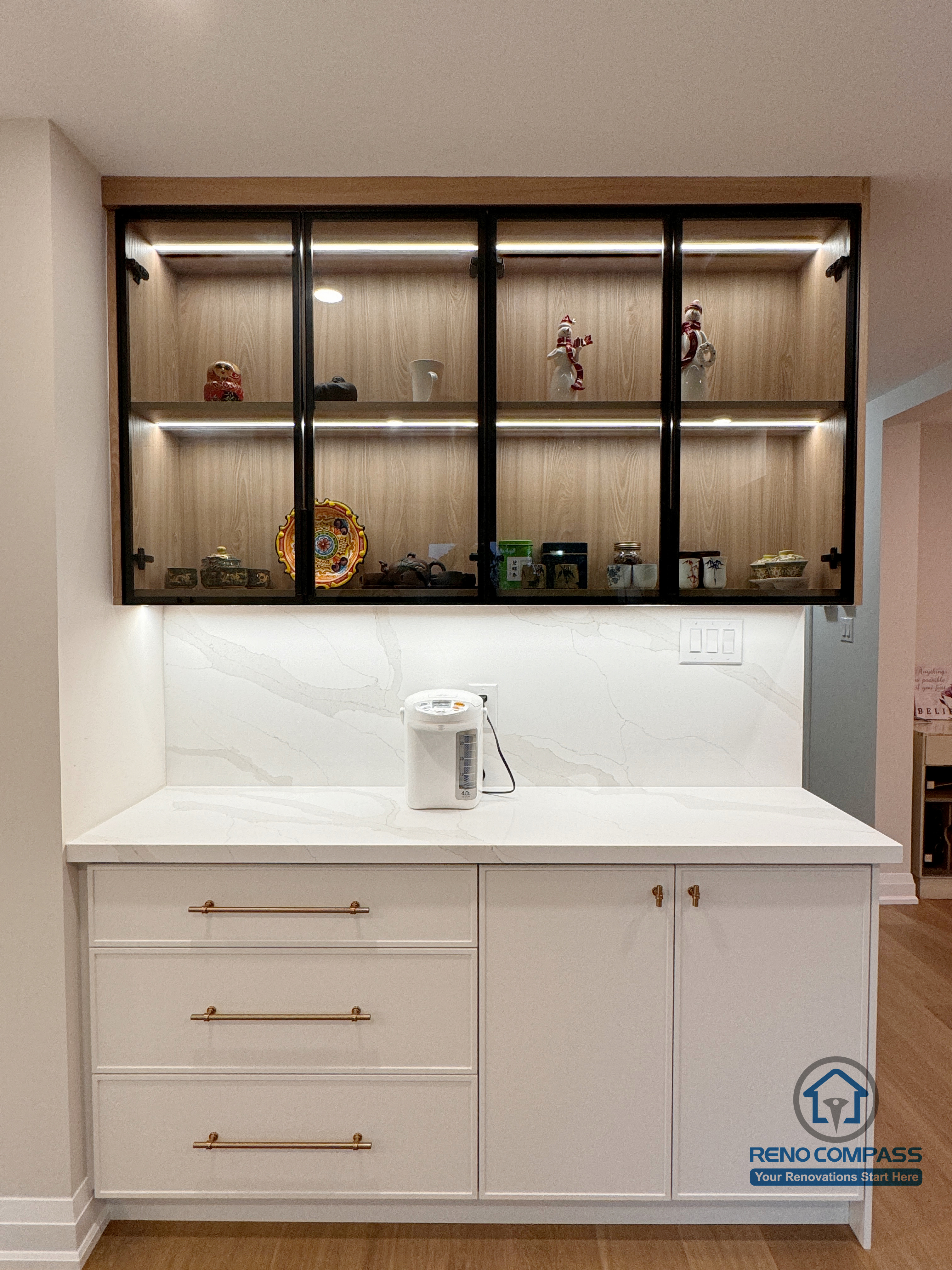 A custom-built display cabinet featuring glass-front doors, warm wood backing, and integrated LED lighting. Designed to combine storage and display, this unit adds depth, warmth, and visual focus to the interior renovation while maintaining a clean, modern aesthetic.