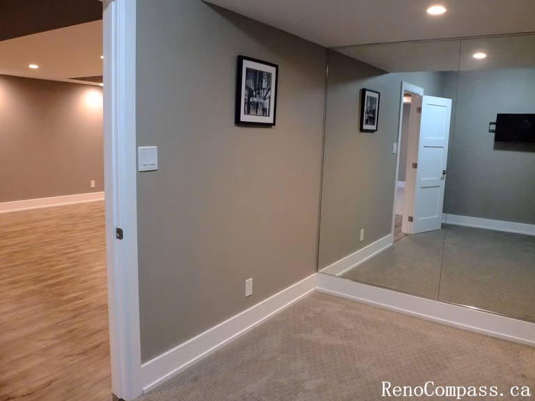 Renovated basement hallway in Waterloo featuring fresh paint, modern white trim and doors, recessed lighting, and new vinyl plank flooring. Clean, functional layout connecting multiple lower‑level rooms.