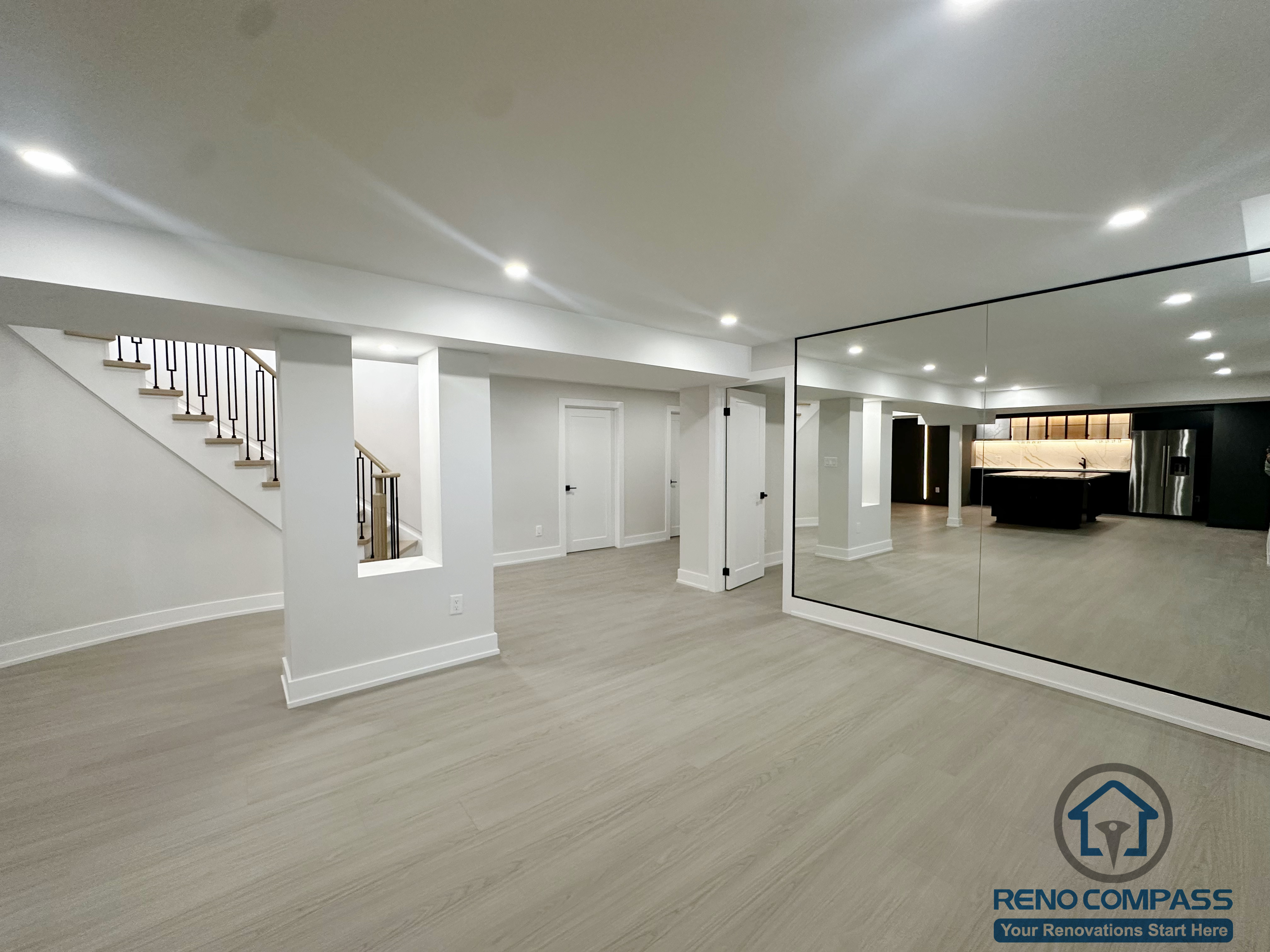 his Markham interior renovation presents a spacious basement layout designed for flexibility and everyday use. The open floor plan allows the space to function as a recreation area, fitness zone, or secondary living space. Structural columns are cleanly integrated to maintain visual order, while recessed ceiling lighting ensures consistent brightness throughout. A full-height mirrored wall enhances the sense of openness and reflects light, making the basement feel larger and more connected to the rest of the home. The result is a practical, modern lower-level space with strong adaptability