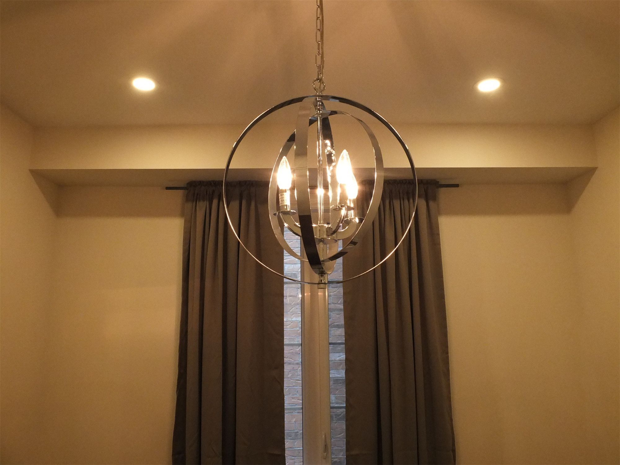 This Kleinburg interior renovation features a contemporary chandelier paired with recessed pot lights, creating a warm and elegant lighting design for the dining area. The modern circular chandelier adds a stylish focal point, while the ceiling pot lights provide balanced illumination throughout the space. Combined with large windows and neutral interior finishes, the lighting enhances the overall ambiance and sophistication of the renovated home.