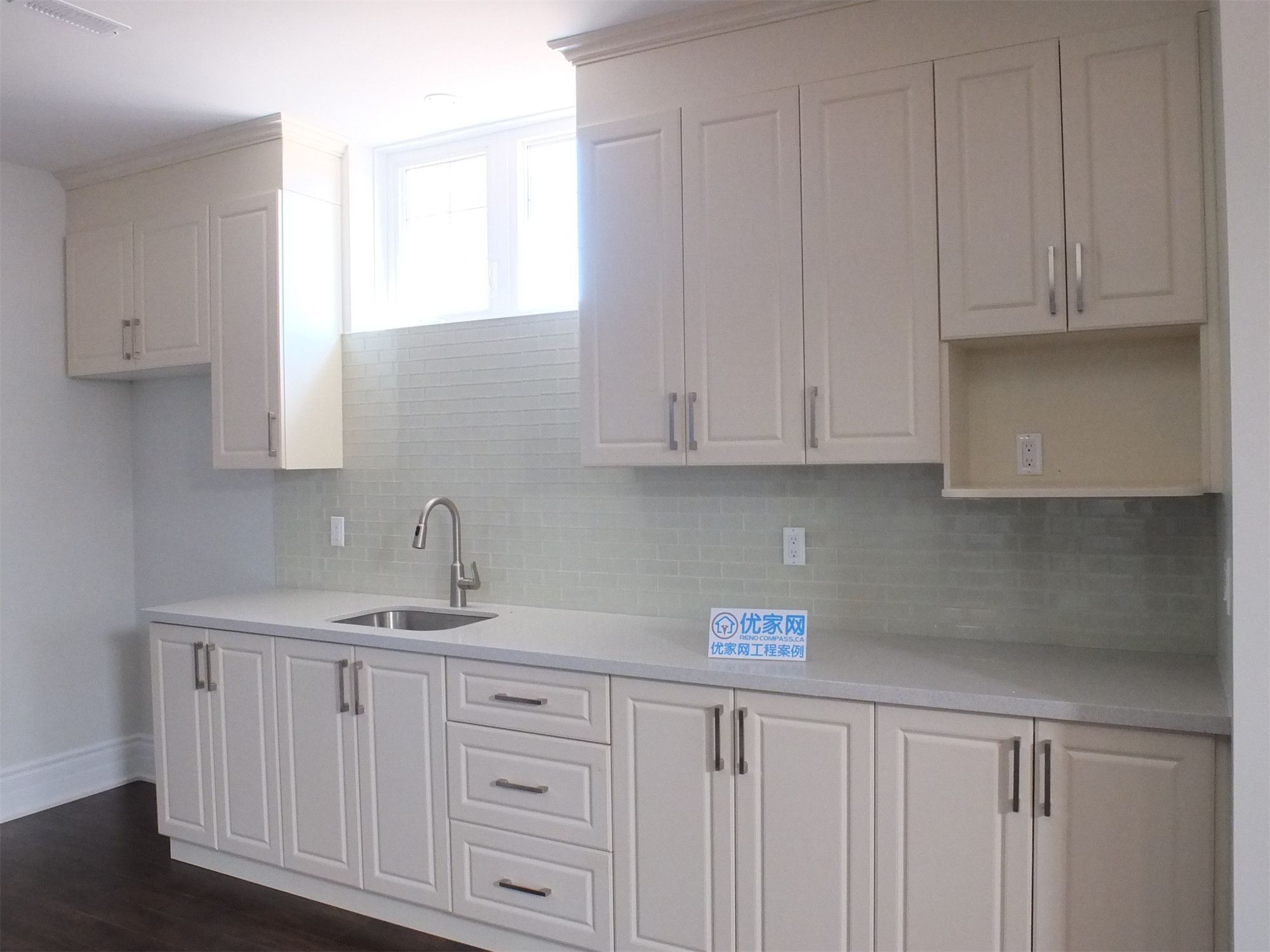 This Richmond Hill basement renovation showcases a bright and functional kitchen area with custom cabinetry, quartz countertops, and a clean backsplash design. Natural light from the window enhances the overall space, making it ideal for a basement kitchen or rental suite setup.