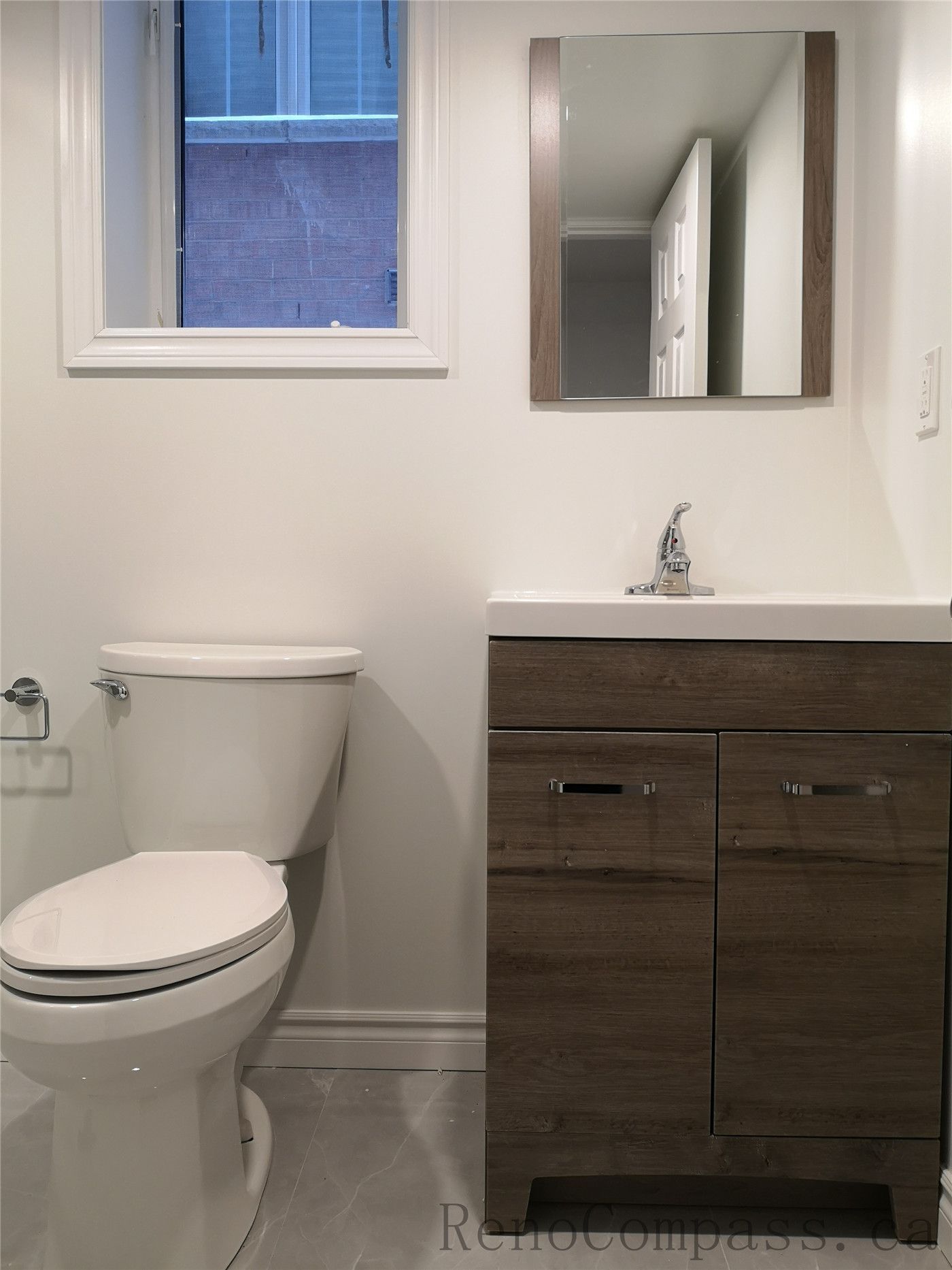 This Richmond Hill basement renovation features a clean and modern bathroom upgrade with a new vanity cabinet, quartz countertop sink, and efficient toilet installation. The neutral wall tones, wood-finish vanity, and bright window lighting create a fresh and functional basement bathroom design. Completed by a professional Toronto renovation company, Reno Compass Inc., this basement bathroom combines practicality, durability, and contemporary style for everyday family use.