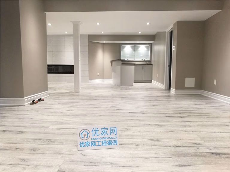 This image showcases a completed Toronto basement renovation featuring an open-concept layout with light wood-grain flooring and neutral wall tones. The space is enhanced with recessed pot lights to improve brightness and overall comfort. A modern bar and functional zones are seamlessly integrated, making the basement ideal for family living, entertainment, or multi-purpose use. This project reflects the quality workmanship and thoughtful layout planning expected from a professional Toronto renovation company.