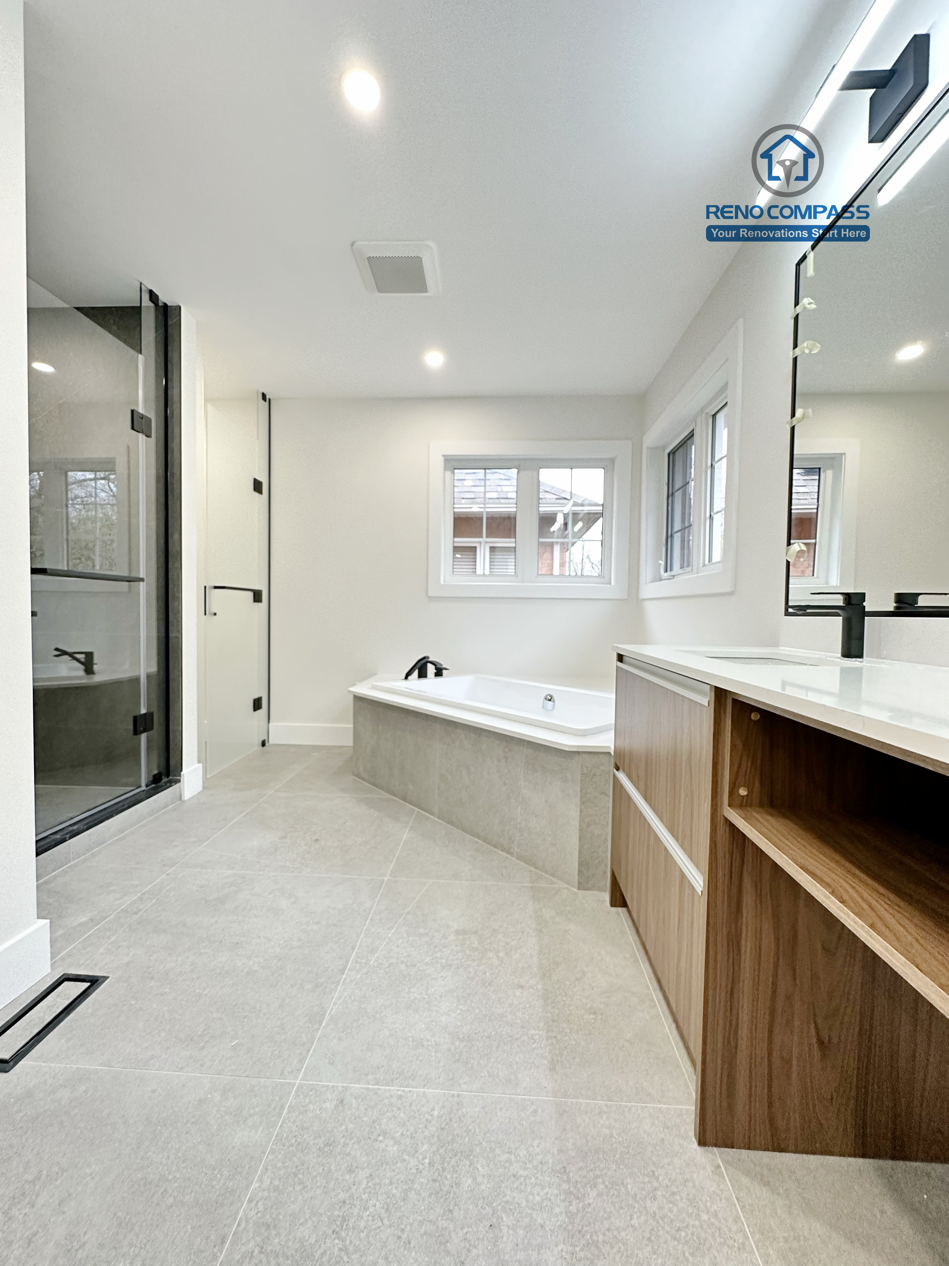 Full bathroom renovation in Richmond Hill showcasing a spacious and open layout with a modern soaking tub, large-format floor tiles, custom vanity cabinetry, and clean architectural lines for a bright and relaxing bathroom space.