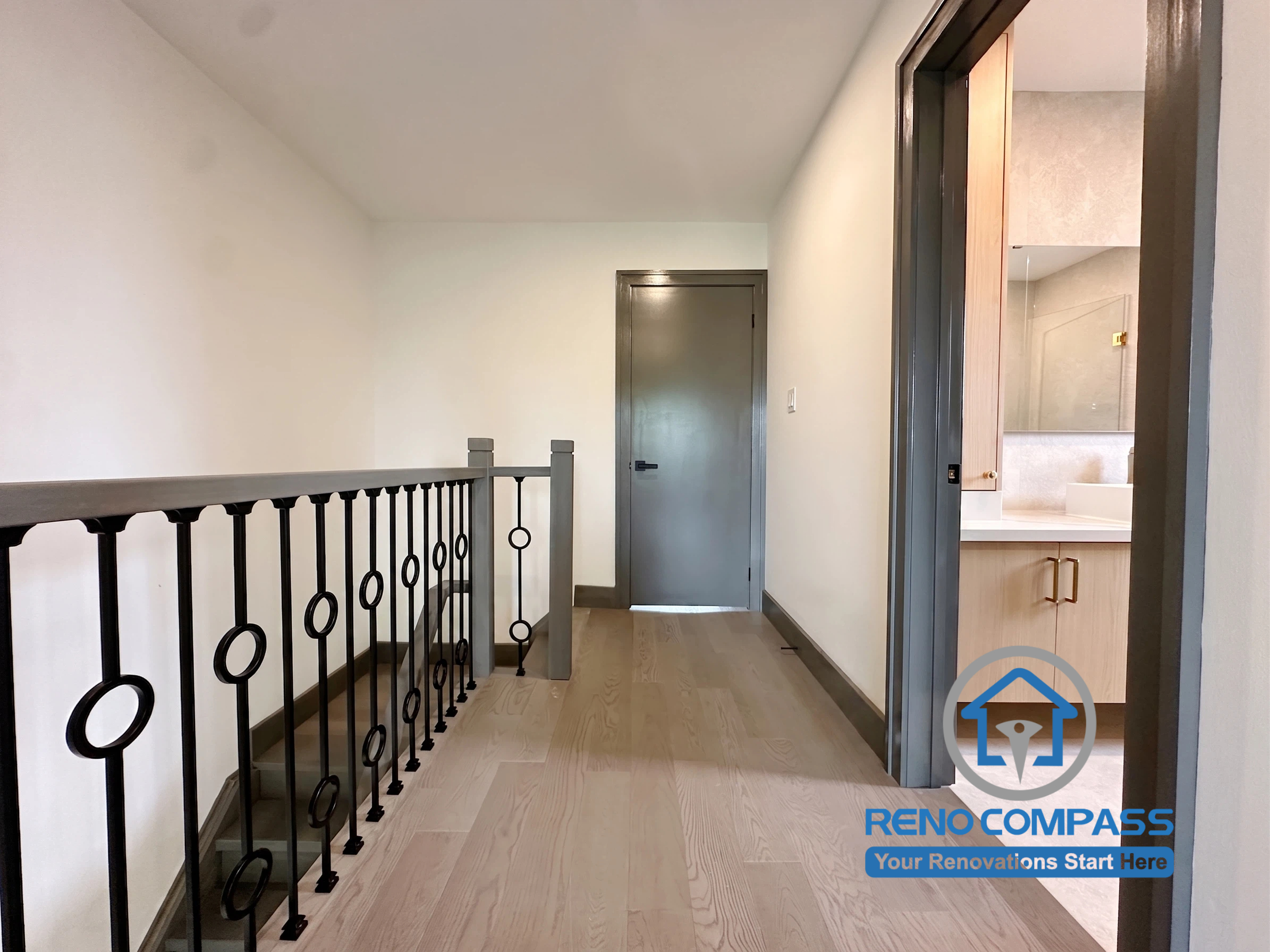 This renovated second-floor hallway features engineered hardwood flooring, custom metal railings, and a clean contemporary design that improves circulation throughout the home. The minimalist finishes and thoughtful detailing create a seamless transition between the bedrooms and bathrooms, contributing to the home's modern aesthetic. Project completed by Reno Compass, serving Markham, Toronto, Richmond Hill, Vaughan, and the Greater Toronto Area.