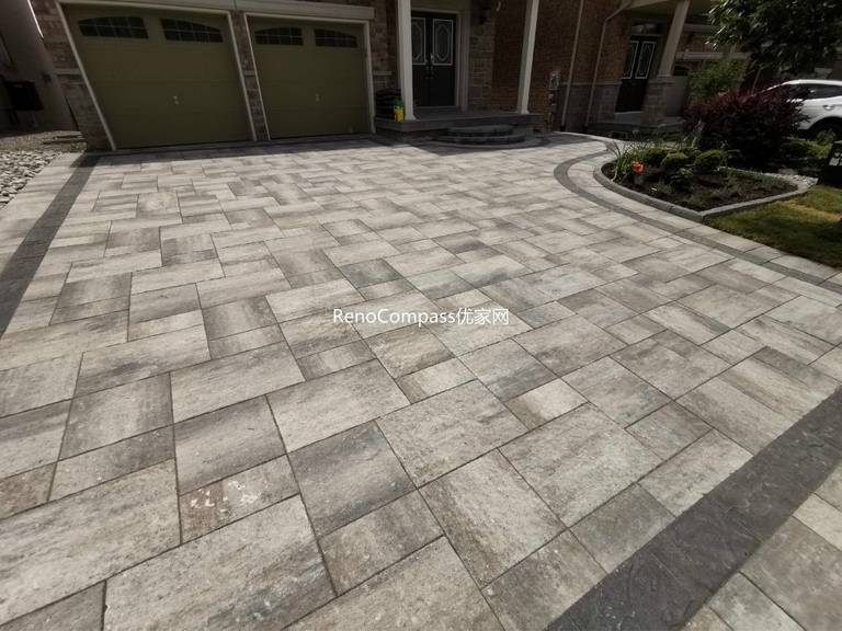 Close-up view of a professionally installed interlocking stone driveway in Vaughan, showcasing high-quality grey pavers, precise alignment, and seamless integration with the front steps and garden edge. Reno Compass delivers premium craftsmanship built to last.