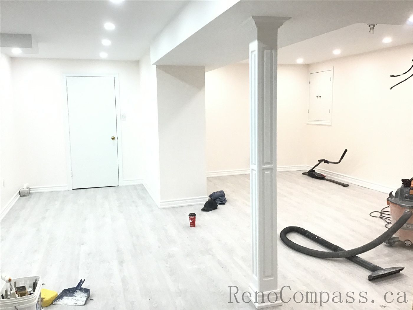 Spacious finished basement renovation in Pickering featuring new light grey vinyl flooring, modern recessed pot lights, and freshly painted walls for a bright contemporary look. Structural columns were refinished to blend seamlessly with the open layout, creating a functional multi-purpose living and recreation space. Completed by Reno Compass Inc., a professional Toronto Renovation Company specializing in basement renovations.