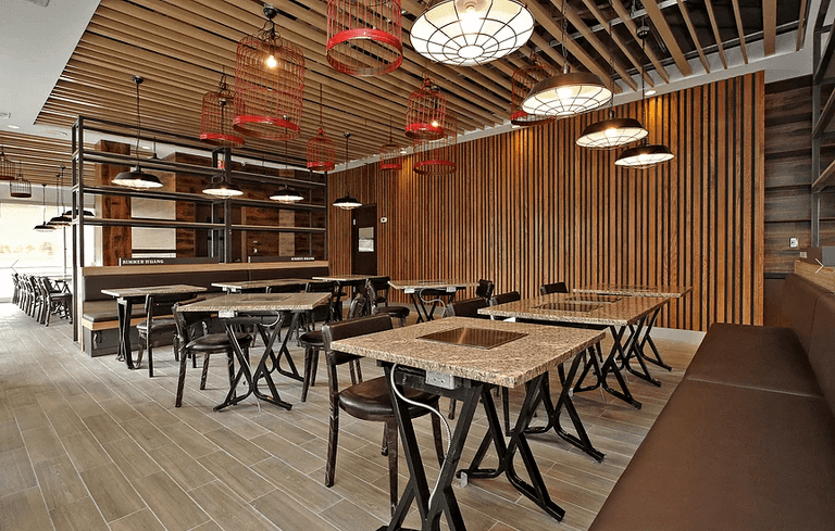 Modern restaurant commercial renovation in Markham featuring custom wood ceiling design, decorative lighting, contemporary wall paneling, and functional dining layout. This professionally designed space enhances customer experience and operational efficiency for restaurant businesses. Completed by a trusted Toronto renovation company, Reno Compass Inc., specializing in commercial and restaurant renovation projects across the GTA.