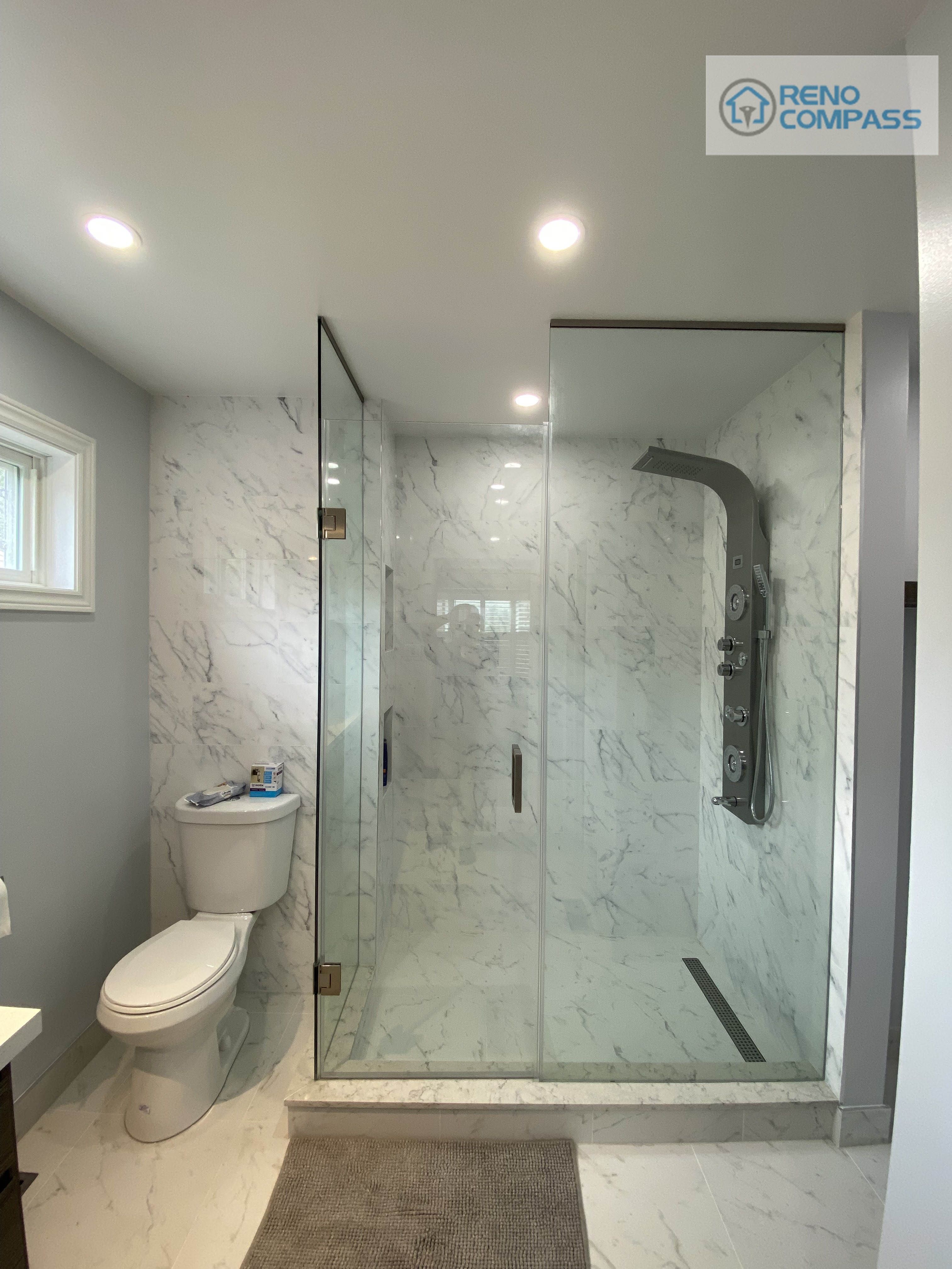 This bathroom renovation in Pickering features a full-size frameless glass walk-in shower, marble-look wall and floor tiles, modern rainfall shower system, and a clean, open layout. The seamless glass enclosure enhances spatial flow while maintaining excellent waterproof performance. Completed by Reno Compass Inc., this bathroom reflects a modern, hotel-inspired design focused on durability and everyday comfort.