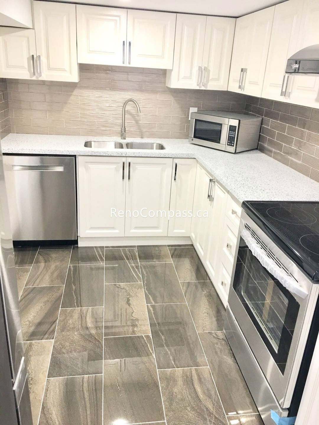 This Toronto basement renovation features a fully upgraded basement kitchen with modern white shaker cabinets, quartz countertops, stainless steel stove, and stylish textured backsplash. The functional layout maximizes storage and cooking space while maintaining a bright, contemporary design. Completed by an experienced Toronto renovation company, this basement kitchen enhances comfort, usability, and property value with quality craftsmanship and durable materials.