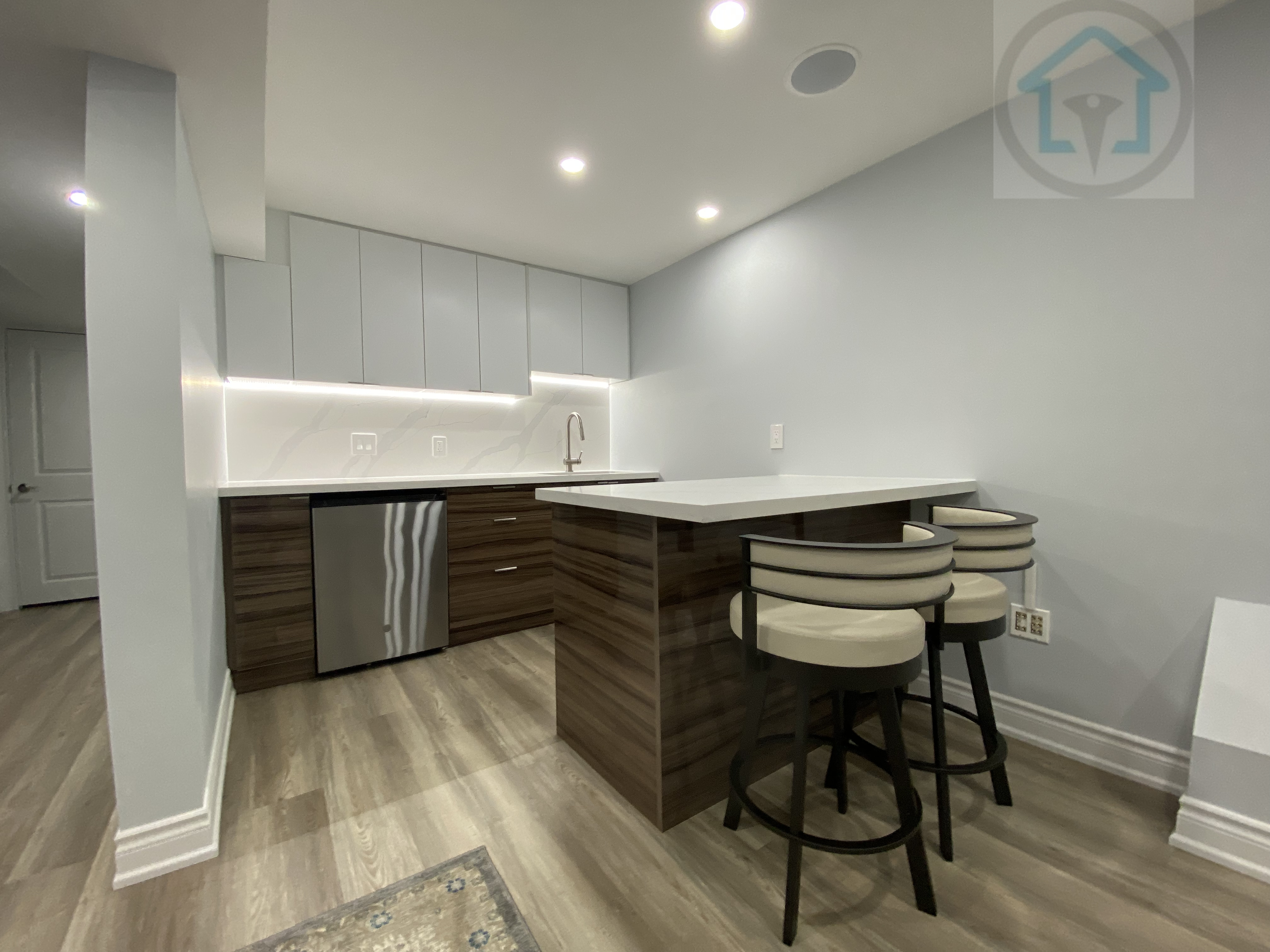 This Vaughan basement renovation highlights a modern kitchen island with bar seating, featuring clean cabinetry, integrated under-cabinet lighting, and durable finishes. The compact layout improves usability and circulation, making the basement kitchen ideal for casual dining, entertaining, and everyday family use.