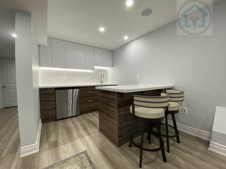 This Vaughan basement renovation highlights a modern kitchen island with bar seating, featuring clean cabinetry, integrated under-cabinet lighting, and durable finishes. The compact layout improves usability and circulation, making the basement kitchen ideal for casual dining, entertaining, and everyday family use.