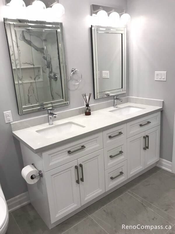 Elegant master bathroom renovation in Markham featuring a white double sink vanity, shaker-style cabinets, and stylish mirrored medicine cabinets with modern vanity lighting.