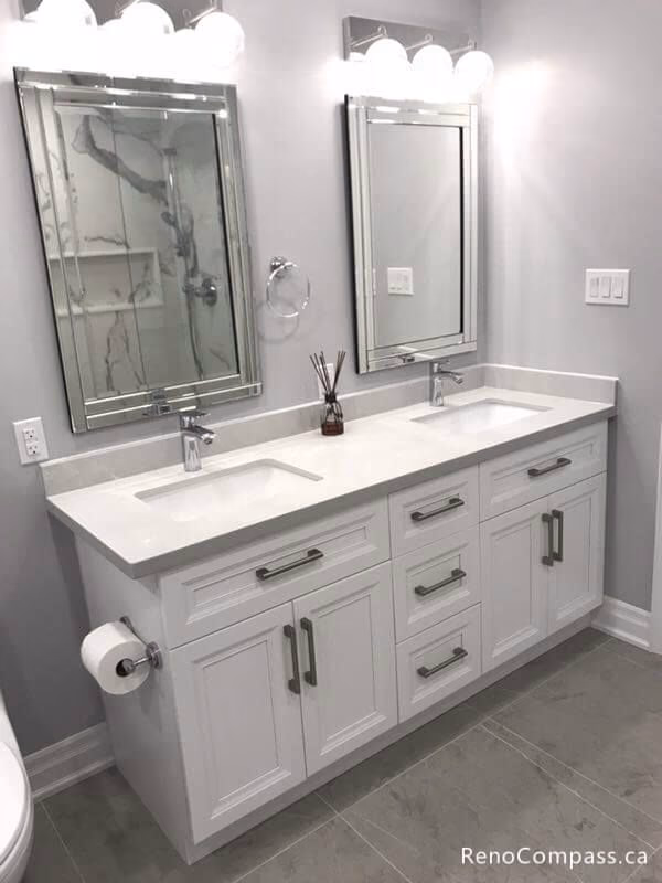 Elegant master bathroom renovation in Markham featuring a white double sink vanity, shaker-style cabinets, and stylish mirrored medicine cabinets with modern vanity lighting.