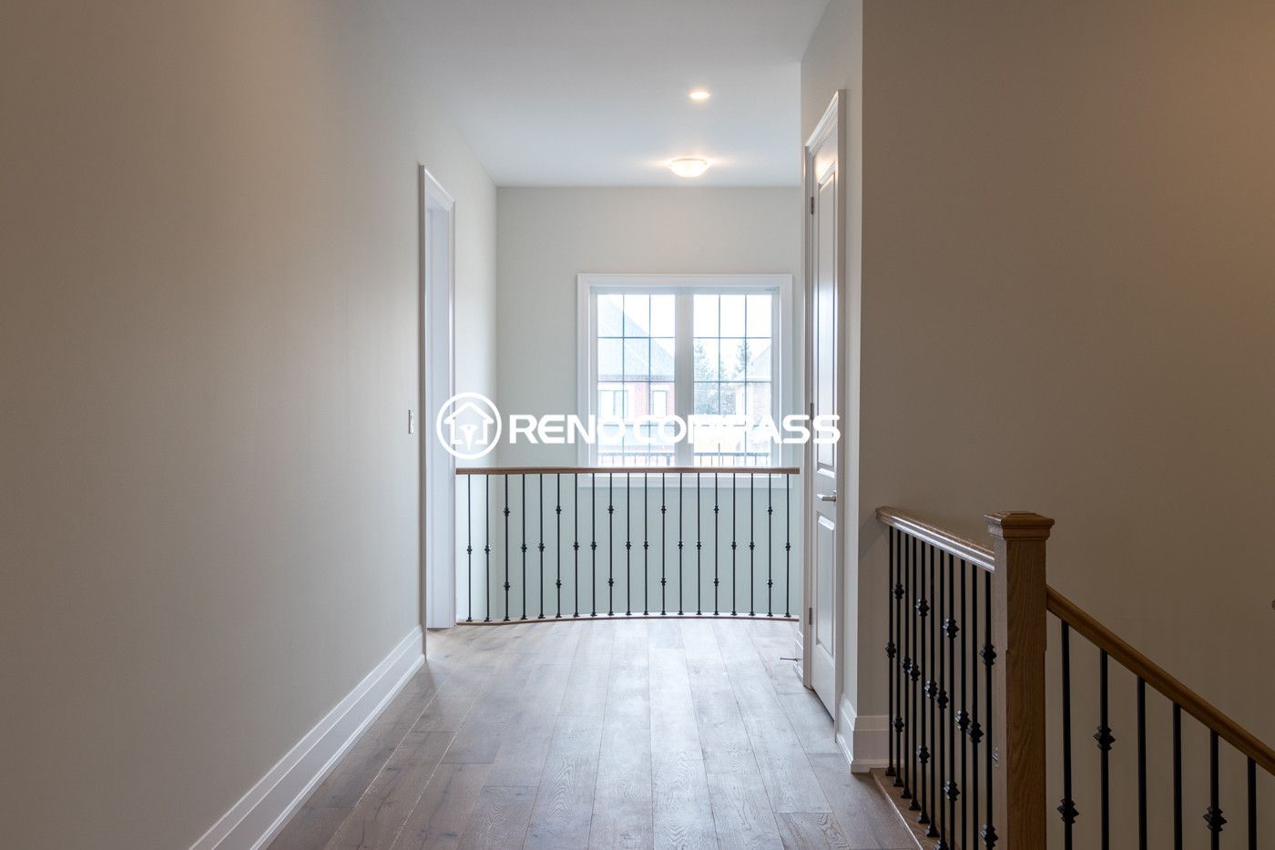 This image shows an upper floor area in a Newmarket home renovation project, featuring professionally installed engineered wood flooring and modern stair railings. The flooring provides a natural hardwood appearance with improved stability and durability. The project was completed by Reno Compass Inc., a Toronto renovation company specializing in flooring and interior renovations.