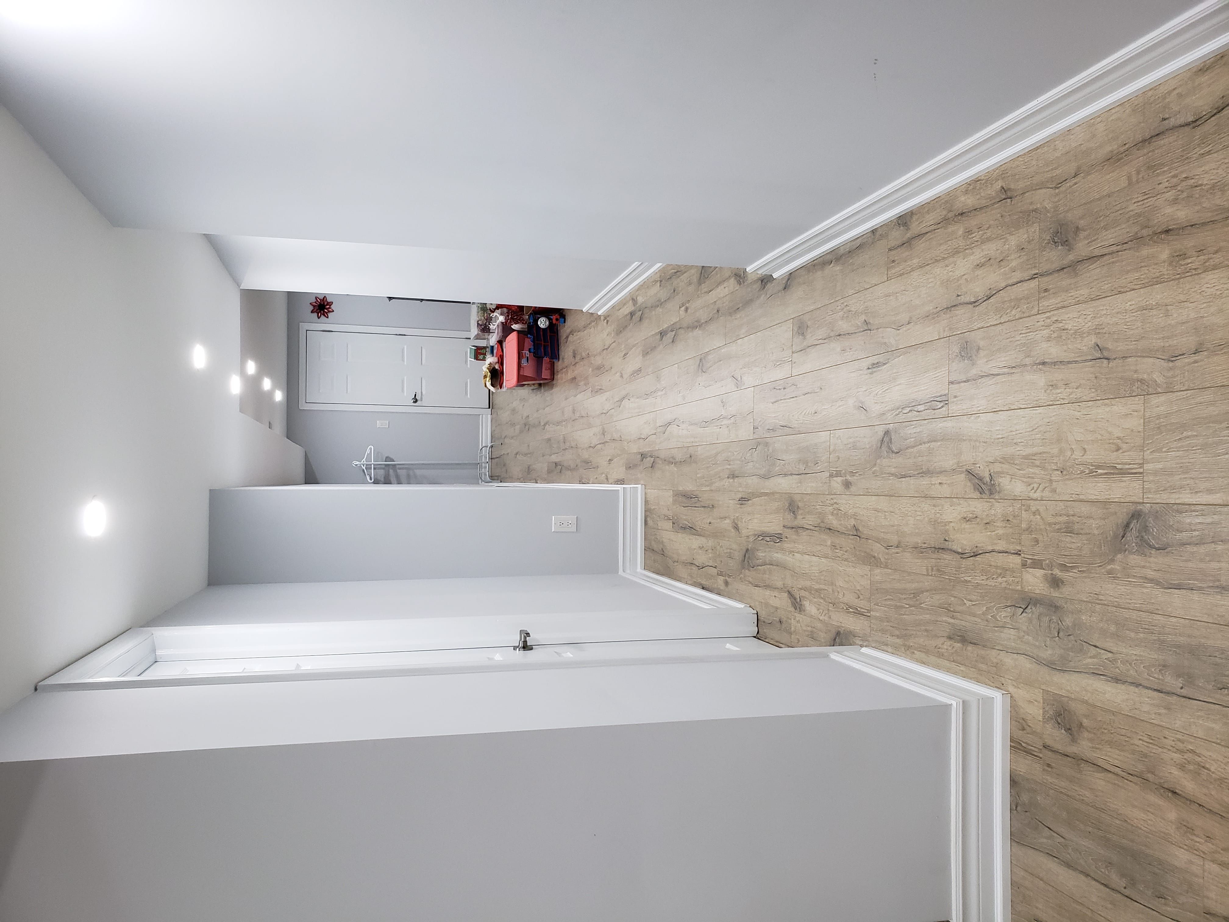 This Newmarket basement renovation showcases upgraded wood-look flooring, modern staircase finishing, and clean white wall detailing for a bright and contemporary look. The space features durable materials, recessed lighting, and a refreshed layout that improves both functionality and visual flow. The neutral color palette enhances the sense of openness, making the basement feel larger and more welcoming. Completed by a trusted Toronto renovation company, this basement finishing project focuses on quality craftsmanship, practical design, and long-lasting performance for everyday family living.