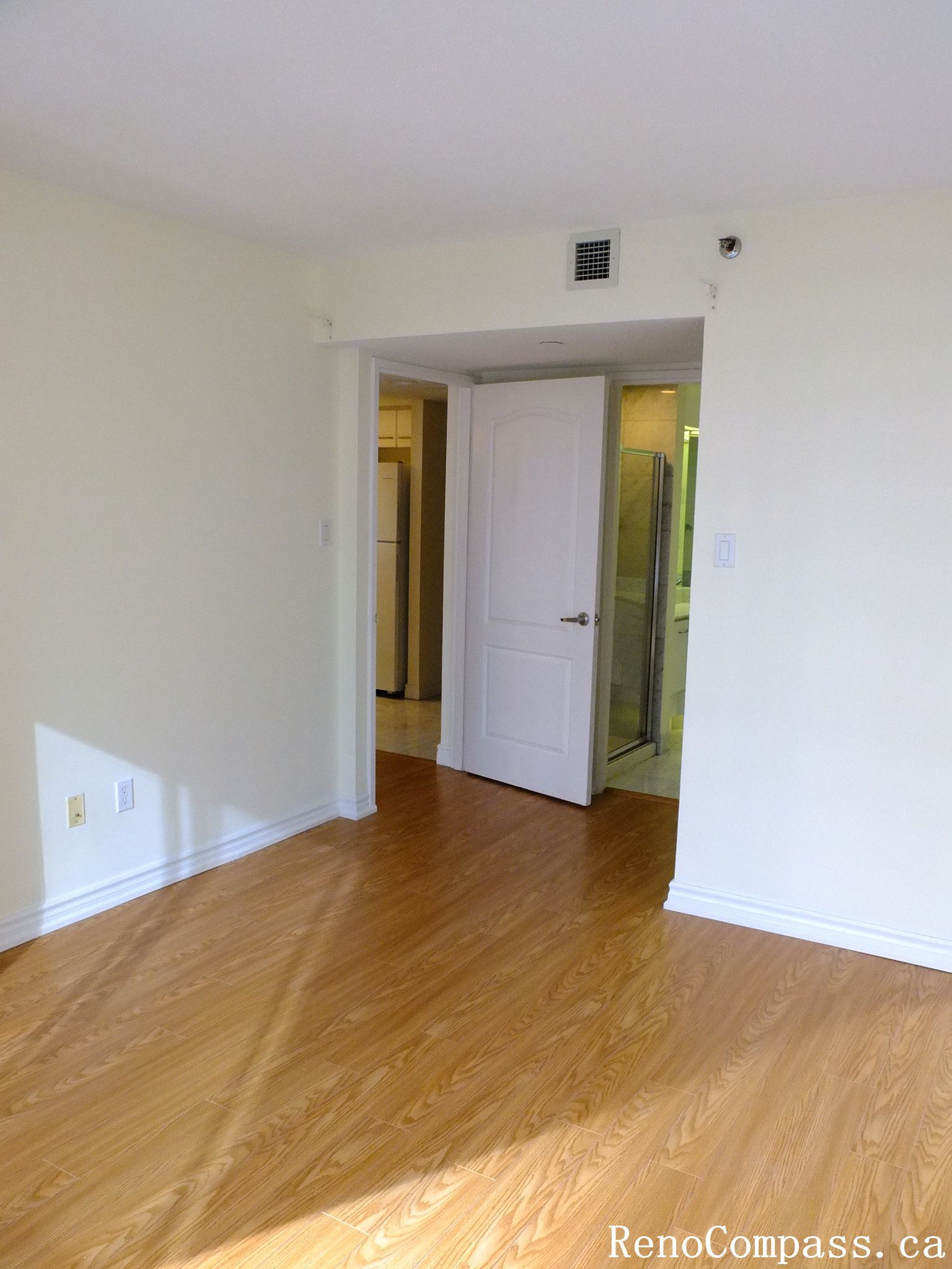 This image shows a bright bedroom in a Toronto condominium before renovation, featuring hardwood flooring and a large window with city views that brings in abundant natural light. As part of a Toronto interior renovation project, the space was prepared for upgrades to improve layout, finishes, and overall modern living comfort.