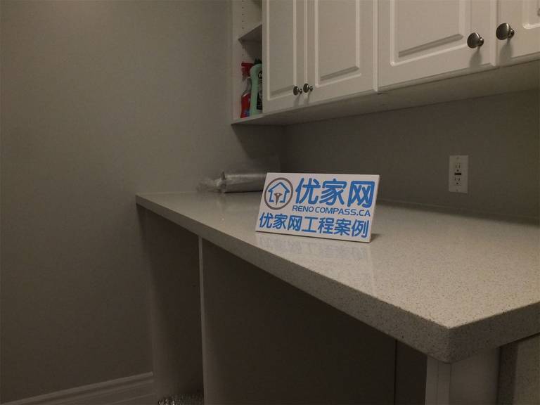 This Richmond Hill basement renovation highlights a detailed view of the utility area, featuring a quartz countertop, custom upper cabinets, and a built-in sink. The clean finishes and practical layout provide efficient storage and workspace, ideal for laundry or additional household use.