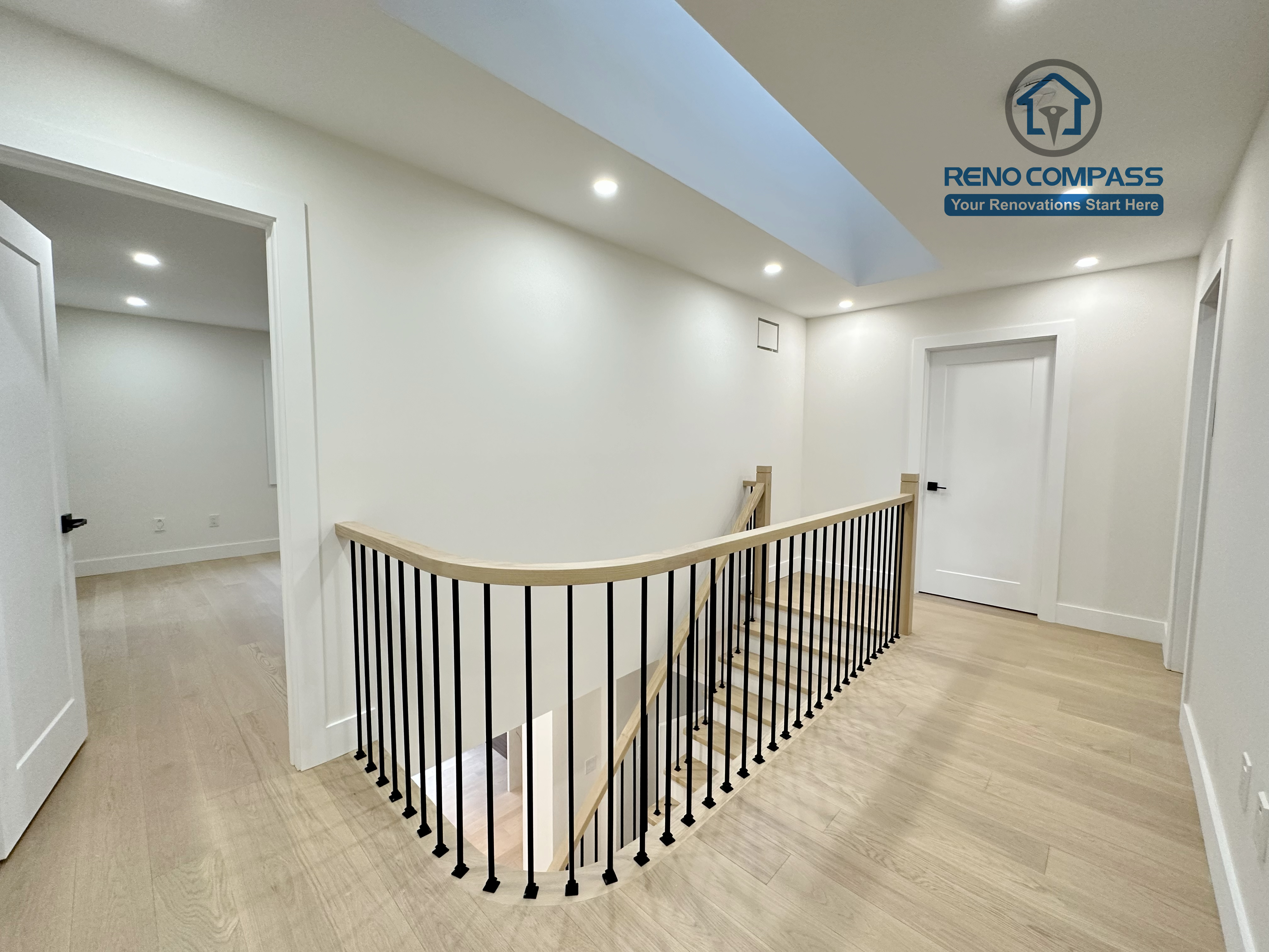 Upper-level hallway in a Richmond Hill home featuring light-tone hardwood flooring, modern stair railings with black balusters, recessed ceiling lights, and skylight-style ceiling detail for a bright, open feel.
