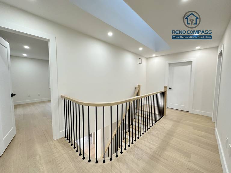 Upper-level hallway in a Richmond Hill home featuring light-tone hardwood flooring, modern stair railings with black balusters, recessed ceiling lights, and skylight-style ceiling detail for a bright, open feel.
