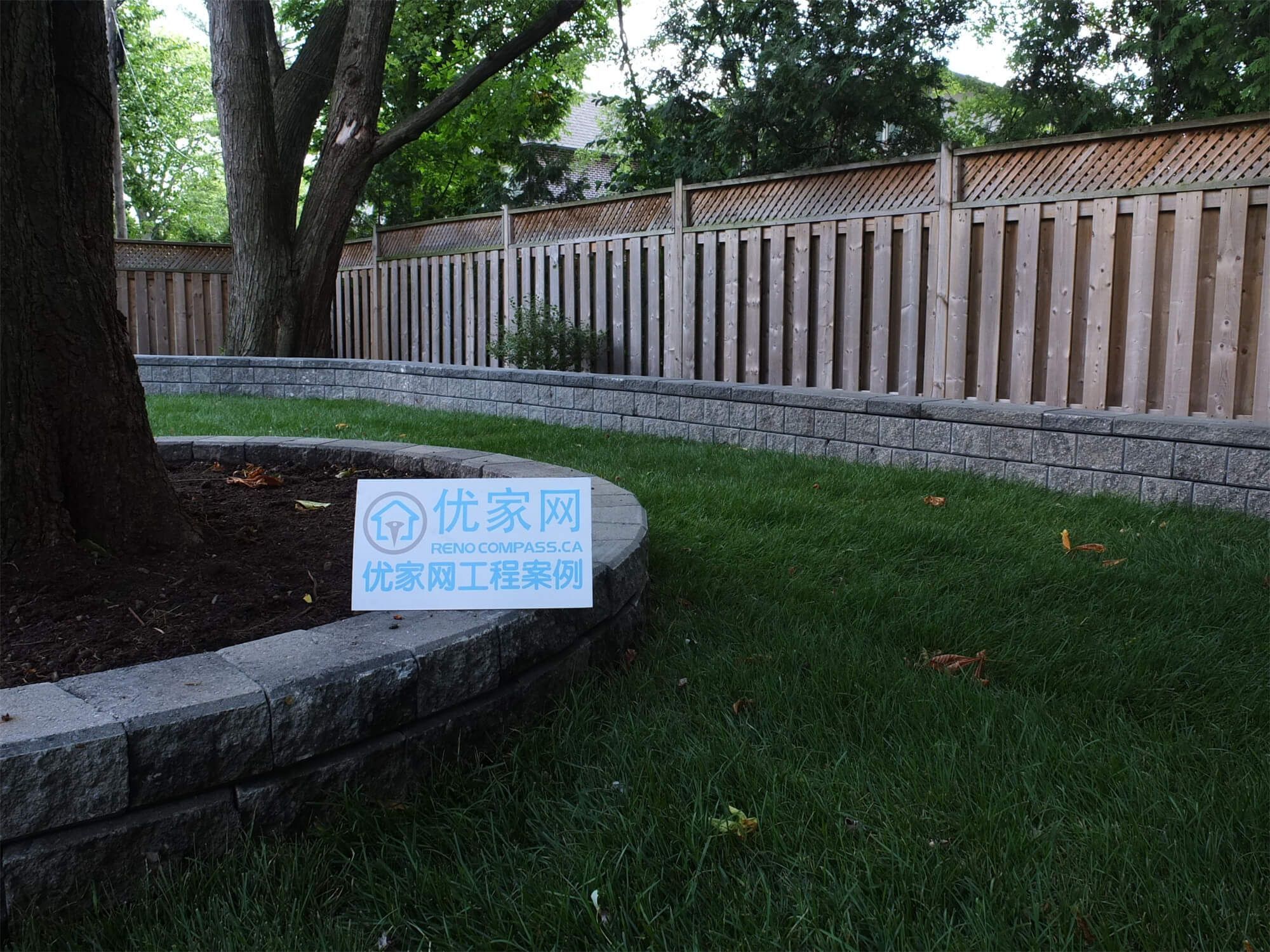 This North York backyard landscaping project highlights a professionally built stone retaining wall designed to create clean lawn separation and improve outdoor structure. The long linear wall adds both visual depth and practical support for the garden and grass area, while the surrounding mature trees and wooden fencing enhance privacy and natural beauty. Completed by Reno Compass, this outdoor upgrade demonstrates expert craftsmanship in retaining wall installation, backyard landscaping, and residential exterior improvement in North York.