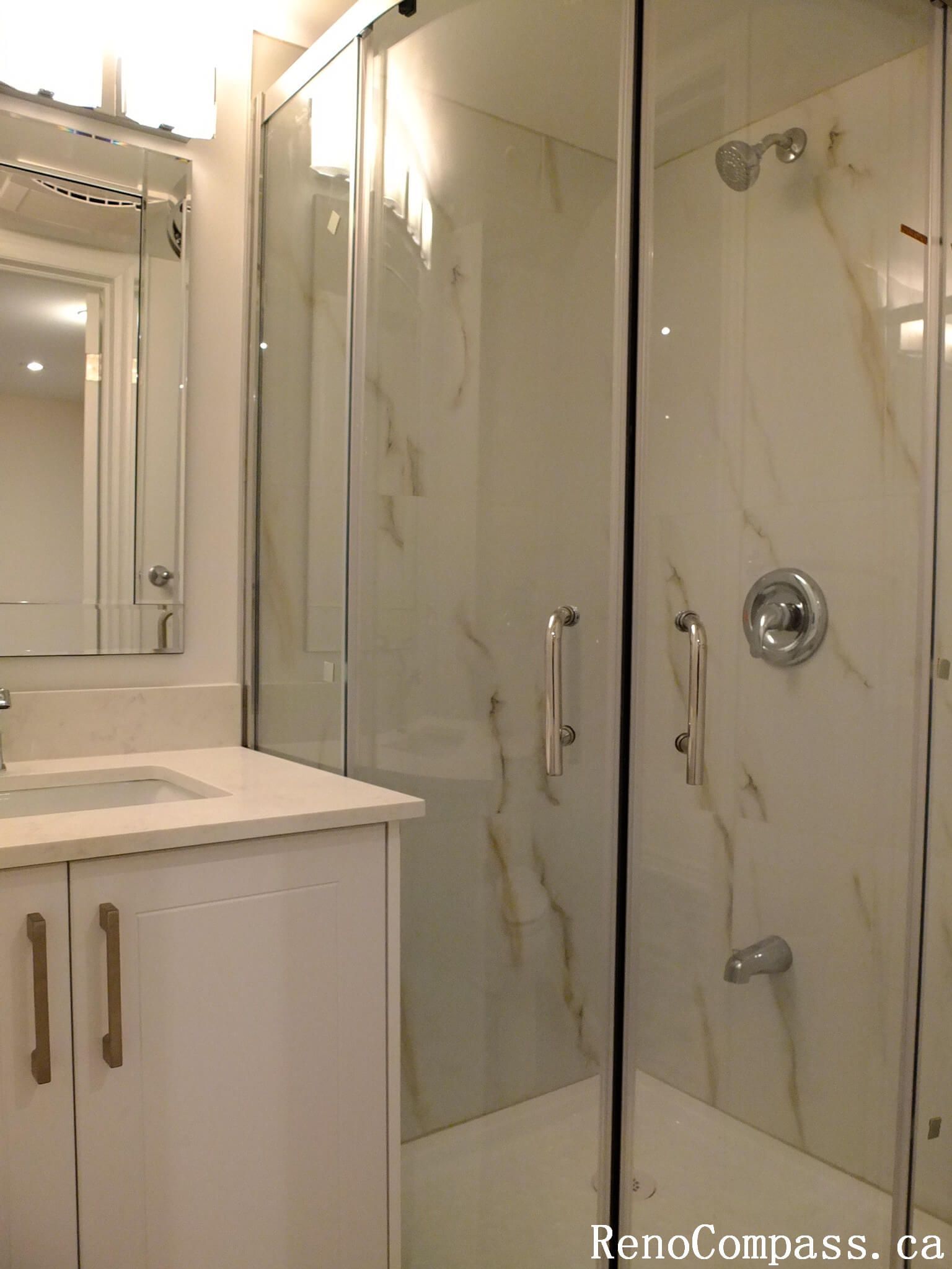 This Markham basement renovation features a modern bathroom design with a frameless glass shower enclosure, marble-look wall tiles, and a sleek white vanity with integrated sink. The bright finishes and contemporary fixtures create a clean, elegant, and highly functional basement bathroom space for homeowners in Markham.