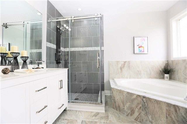 A beautifully remodeled bathroom featuring a frameless glass shower, sleek white vanity, and neutral tile design. Perfect inspiration for a modern home renovation in the Greater Toronto Area.